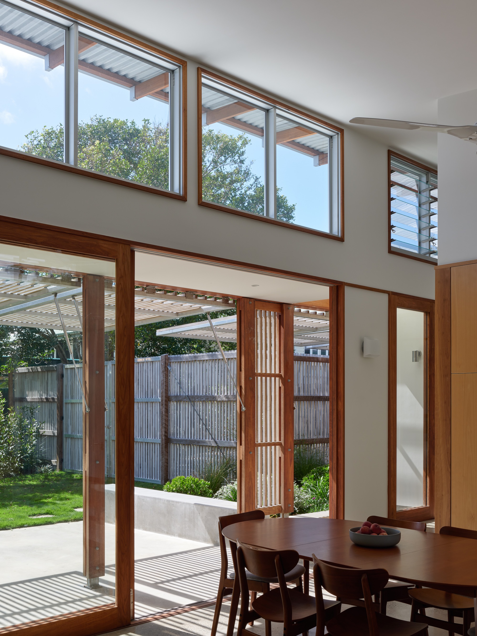 Dining area with timber-framed glazing looking out to the screened courtyard and clerestory windows above