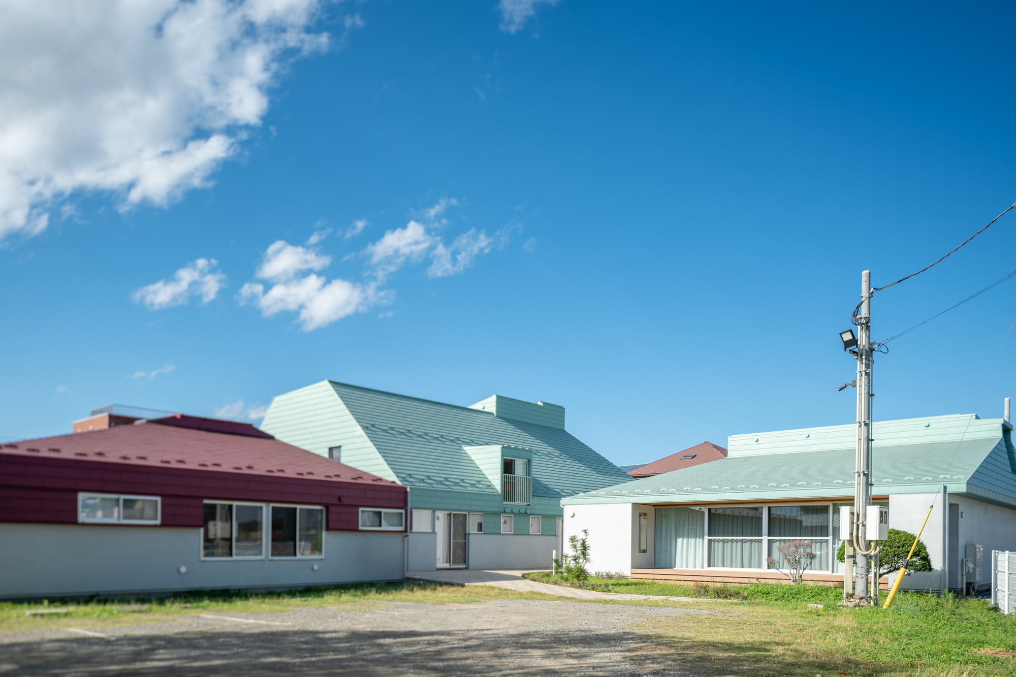 Cluster of gabled roofs in maroon and pale green metal under a blue sky with clouds