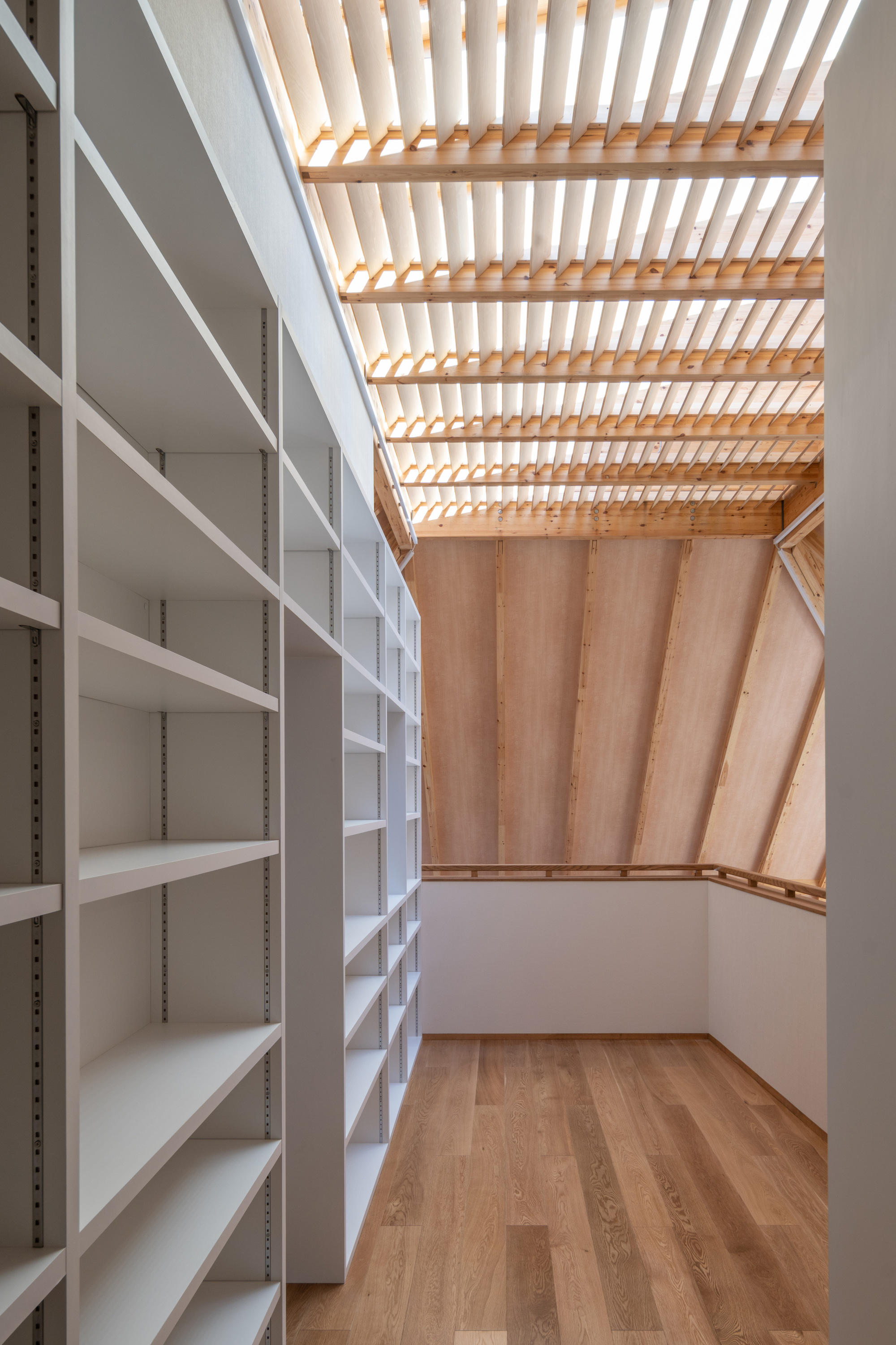 Storage room with white adjustable shelving beneath a slatted timber skylight