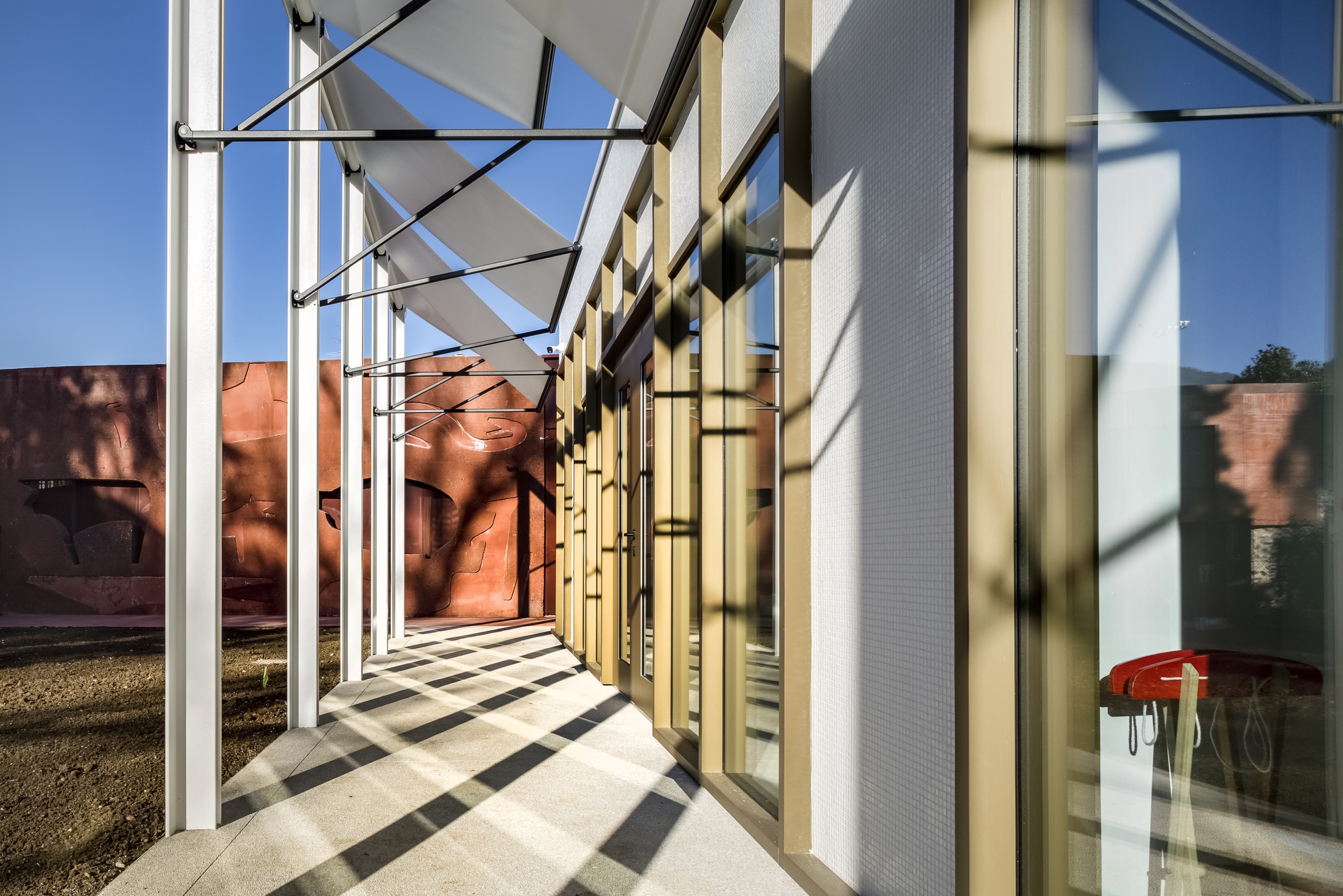 Exterior corridor with white steel columns and shadows falling across the polished concrete floor