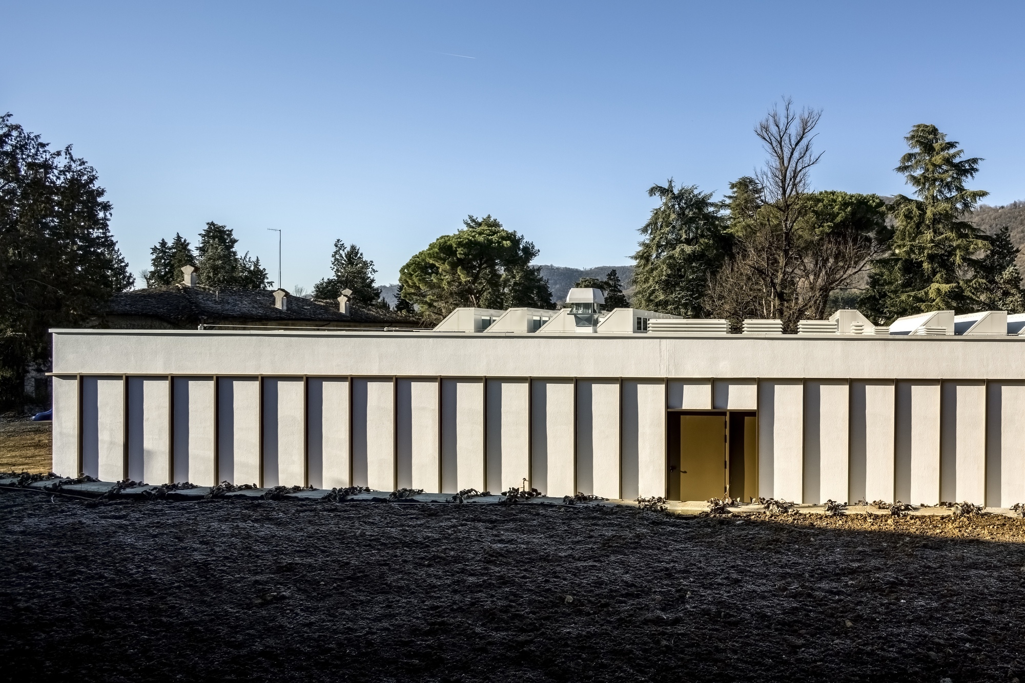 Exterior view of the striped facade with vertical cream and dark panels under a clear blue sky
