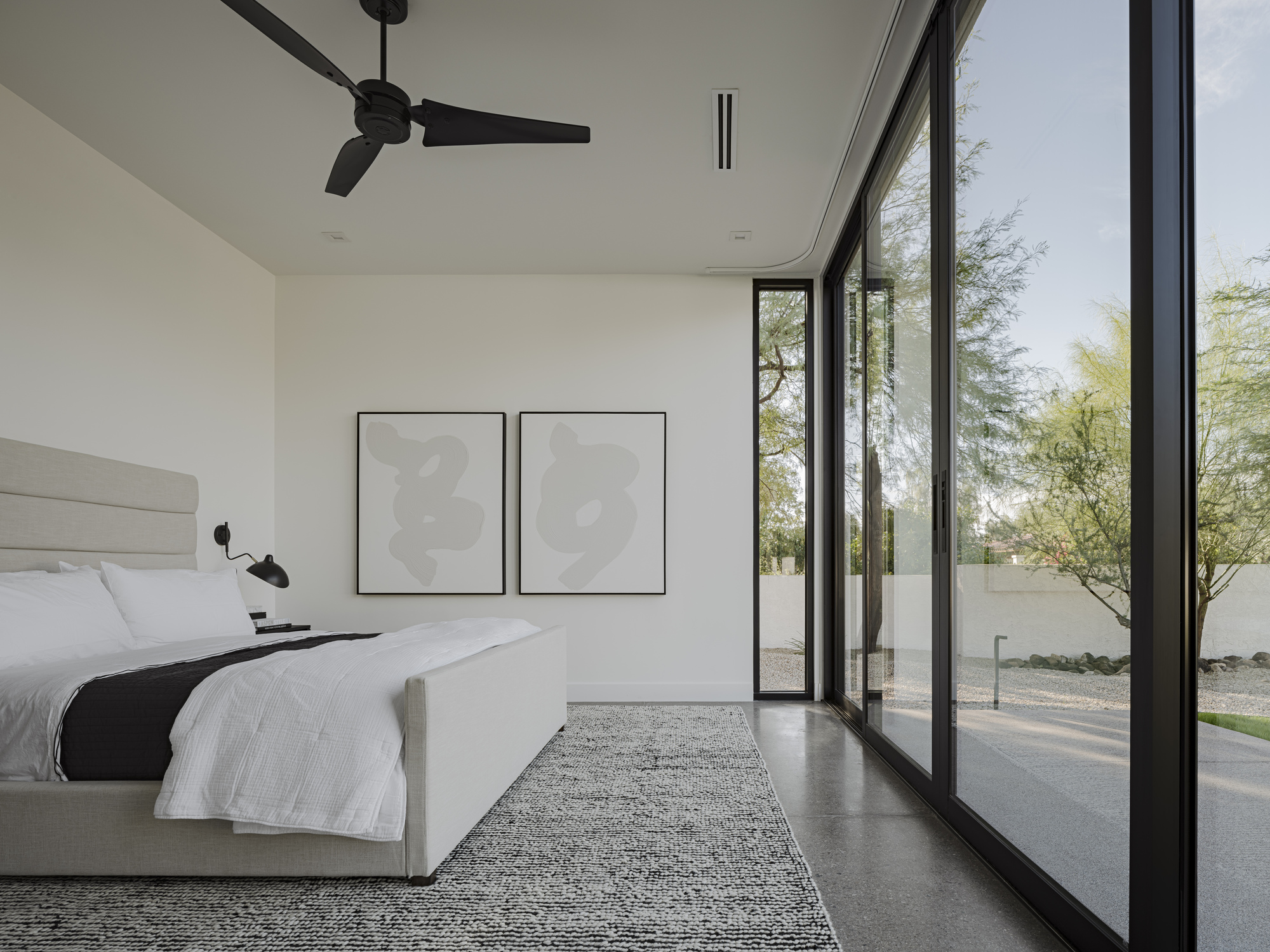 Bedroom with corner glazing opening to gravel courtyard and native desert trees