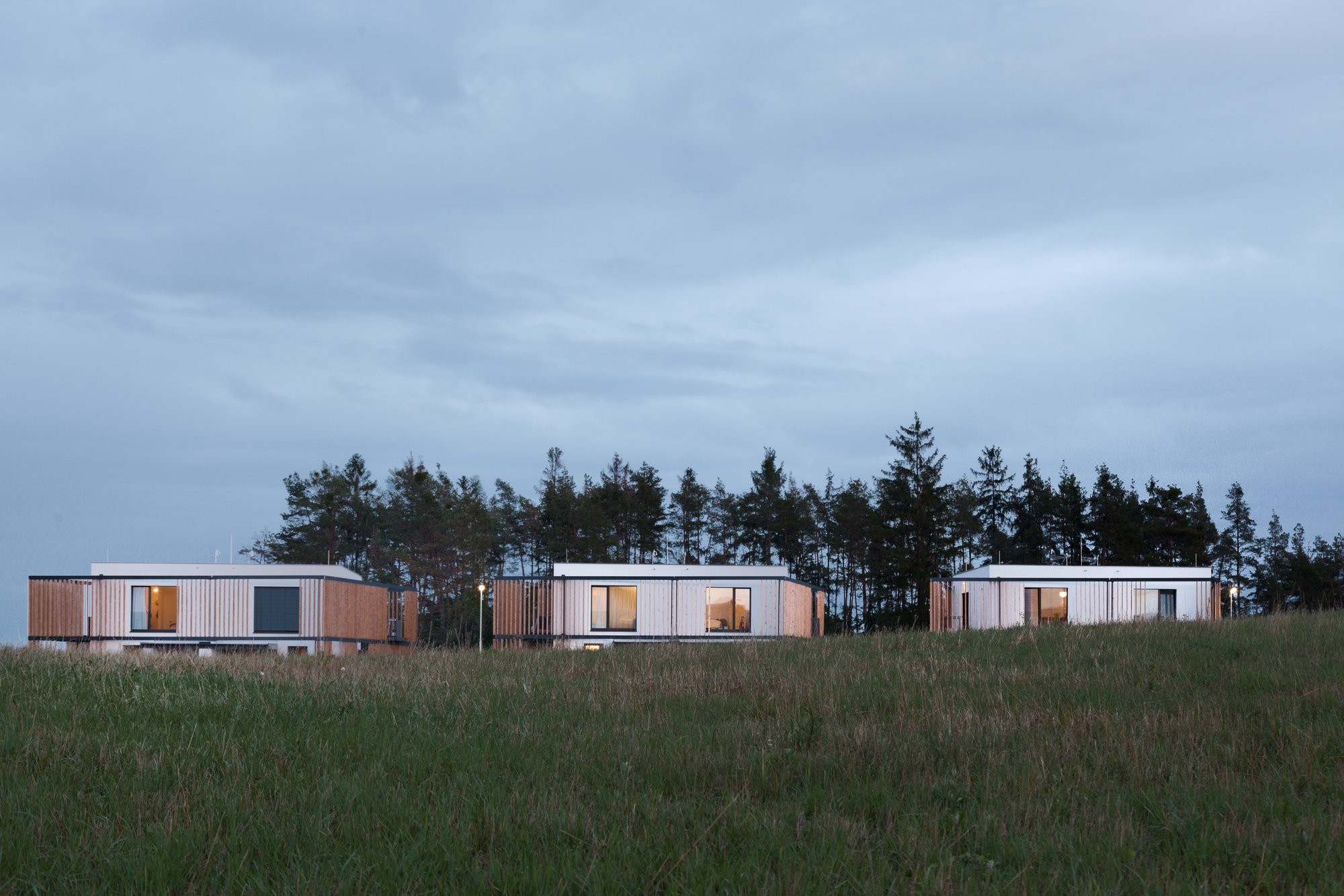 Minimal cubic forms sit lightly within the landscape, opening selectively toward distant views while maintaining enclosure.