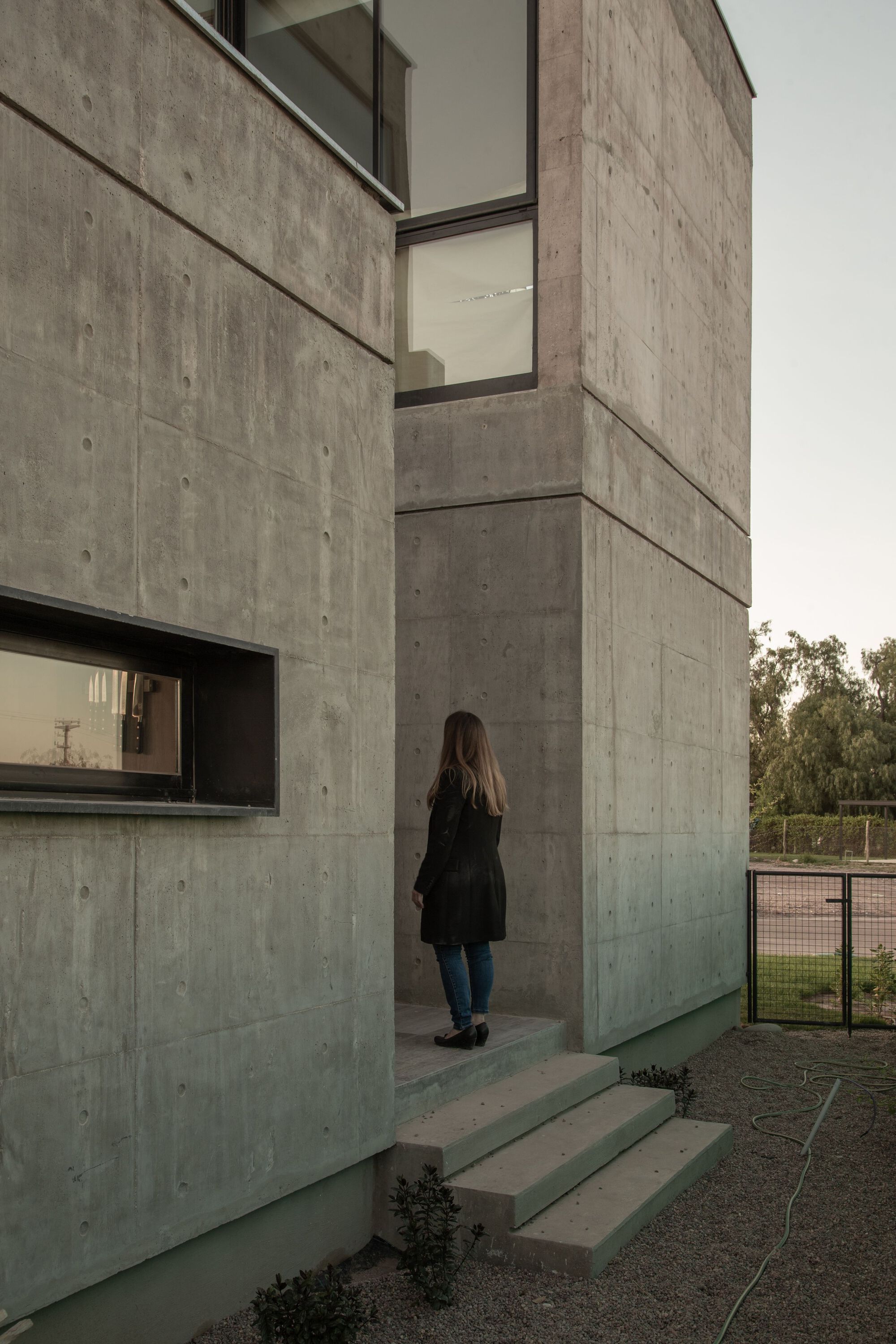 Concrete entry steps with a person approaching the recessed doorway in overcast light