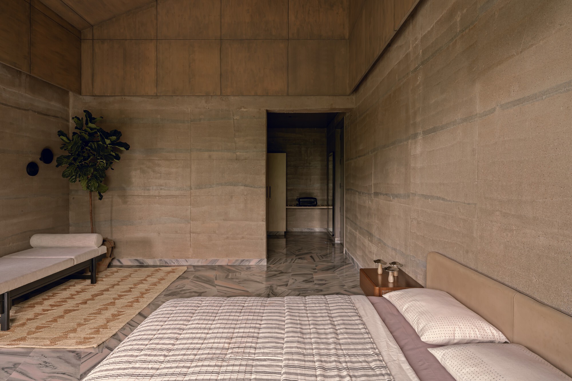 Interior courtyard with rammed earth walls, herringbone stone floor and low platform seating in shadow