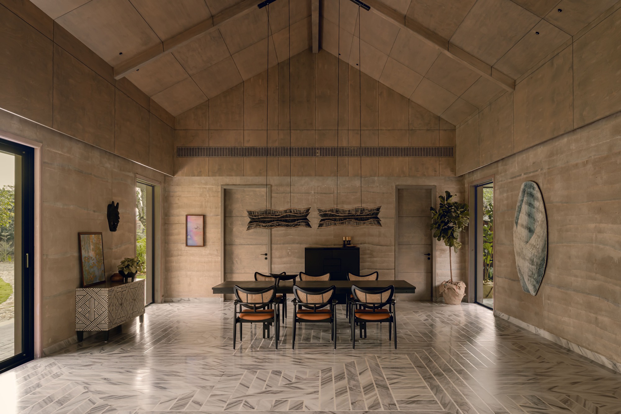 Dining room with vaulted ceiling panels, rammed earth walls and herringbone floor in natural daylight