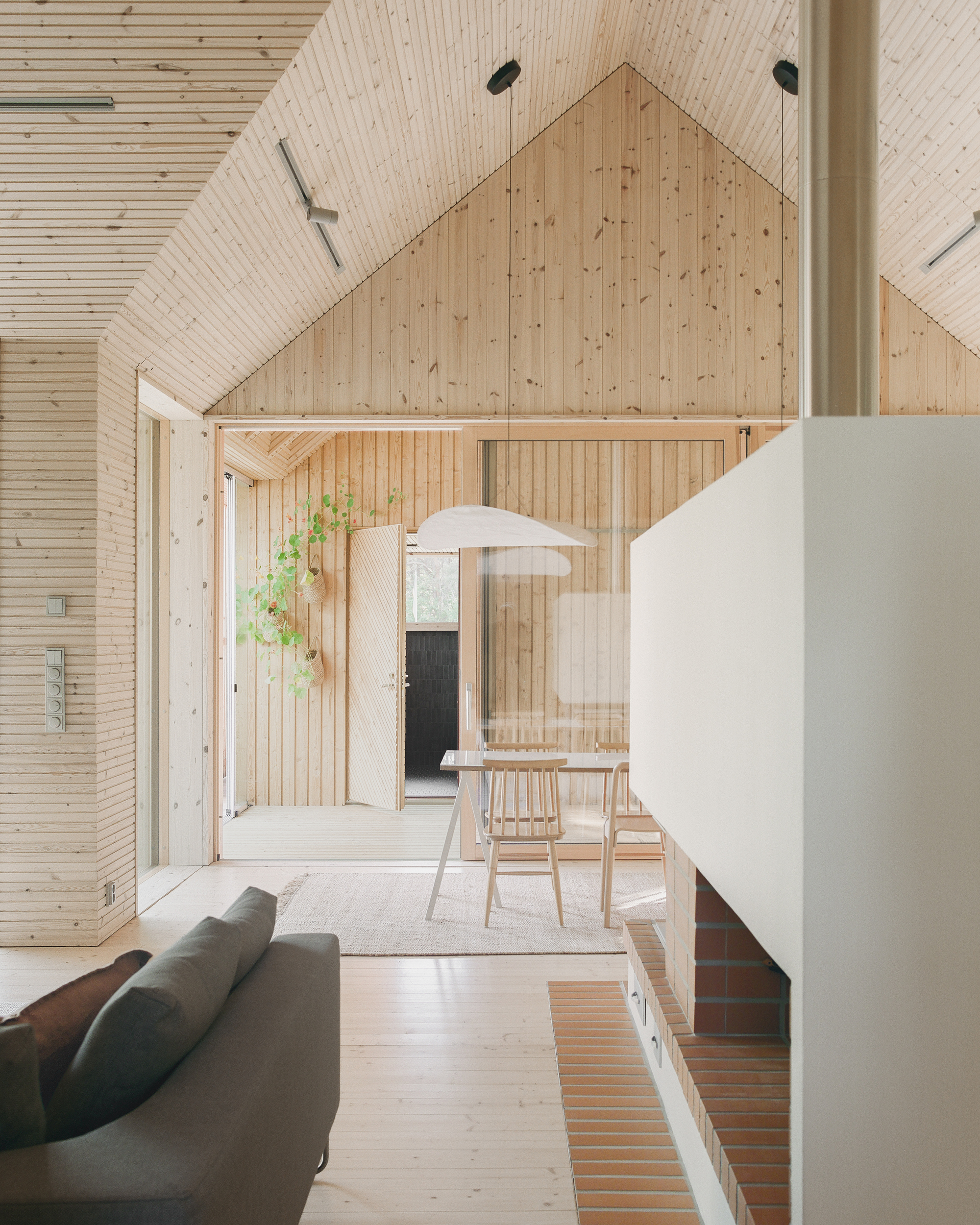 Interior view of timber-lined living space with exposed gable ceiling and white fireplace volume