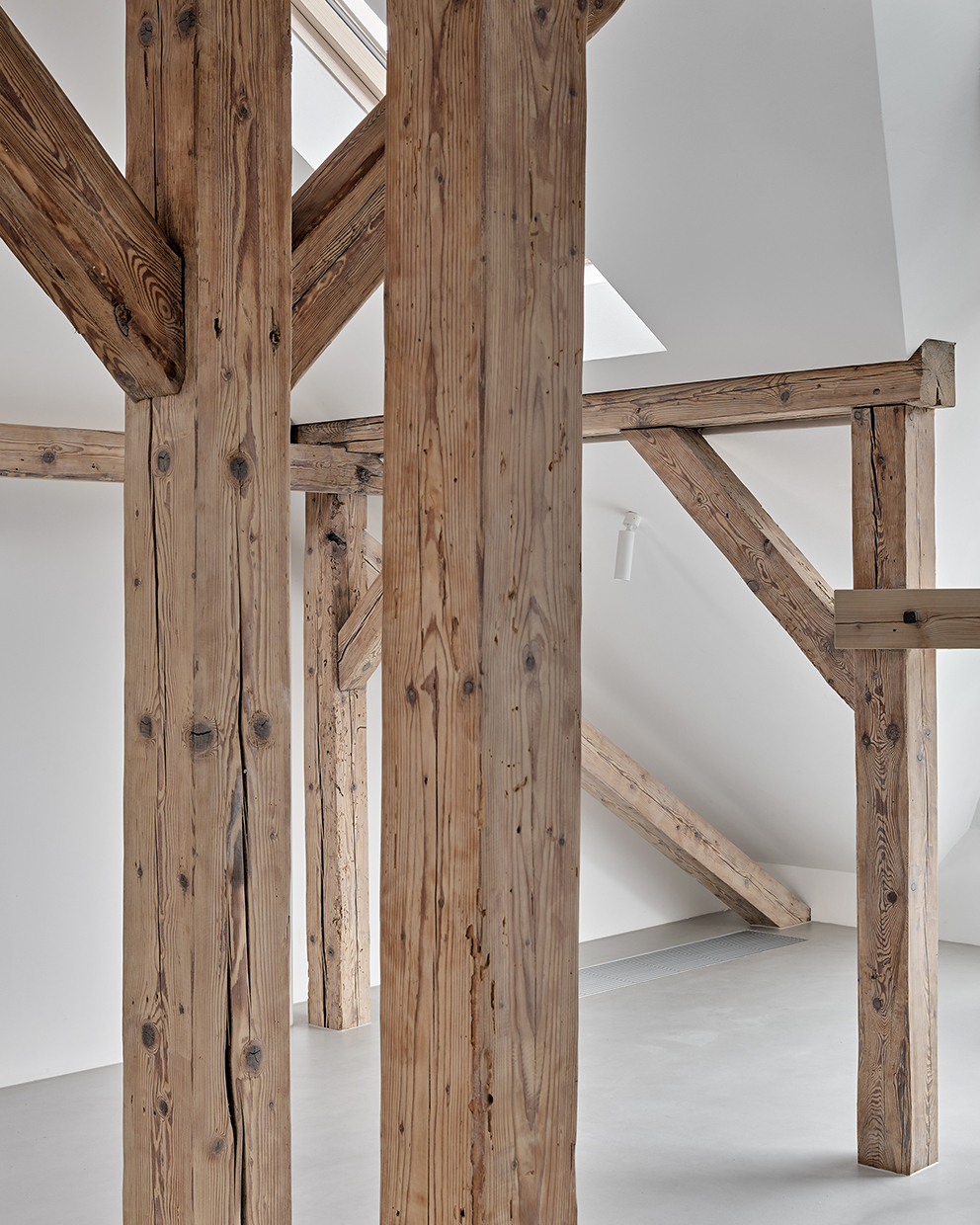 Close-up of reclaimed timber post and beam joinery with white plaster walls in background