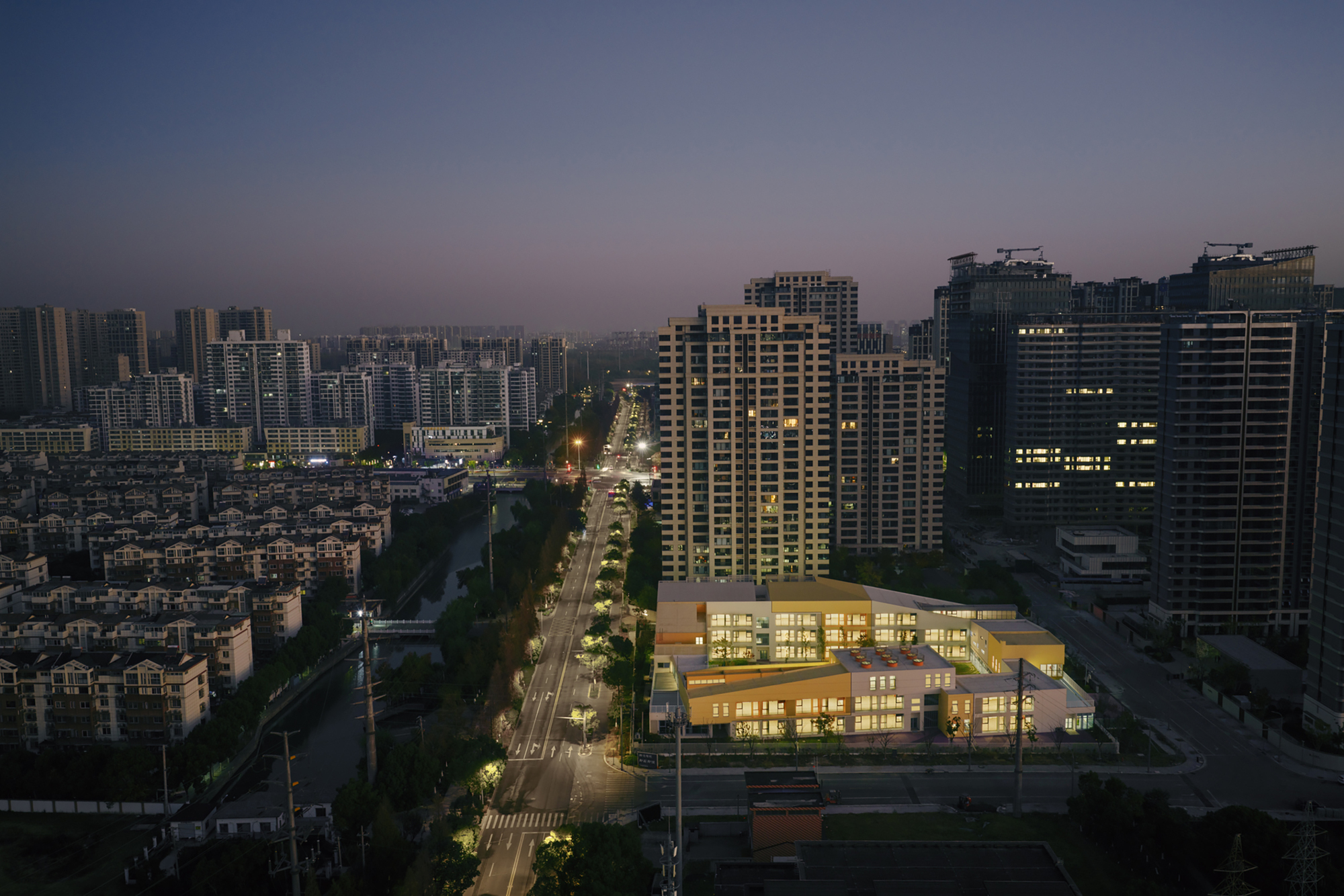 Twilight view of the illuminated facade with glass curtain walls along the street edge