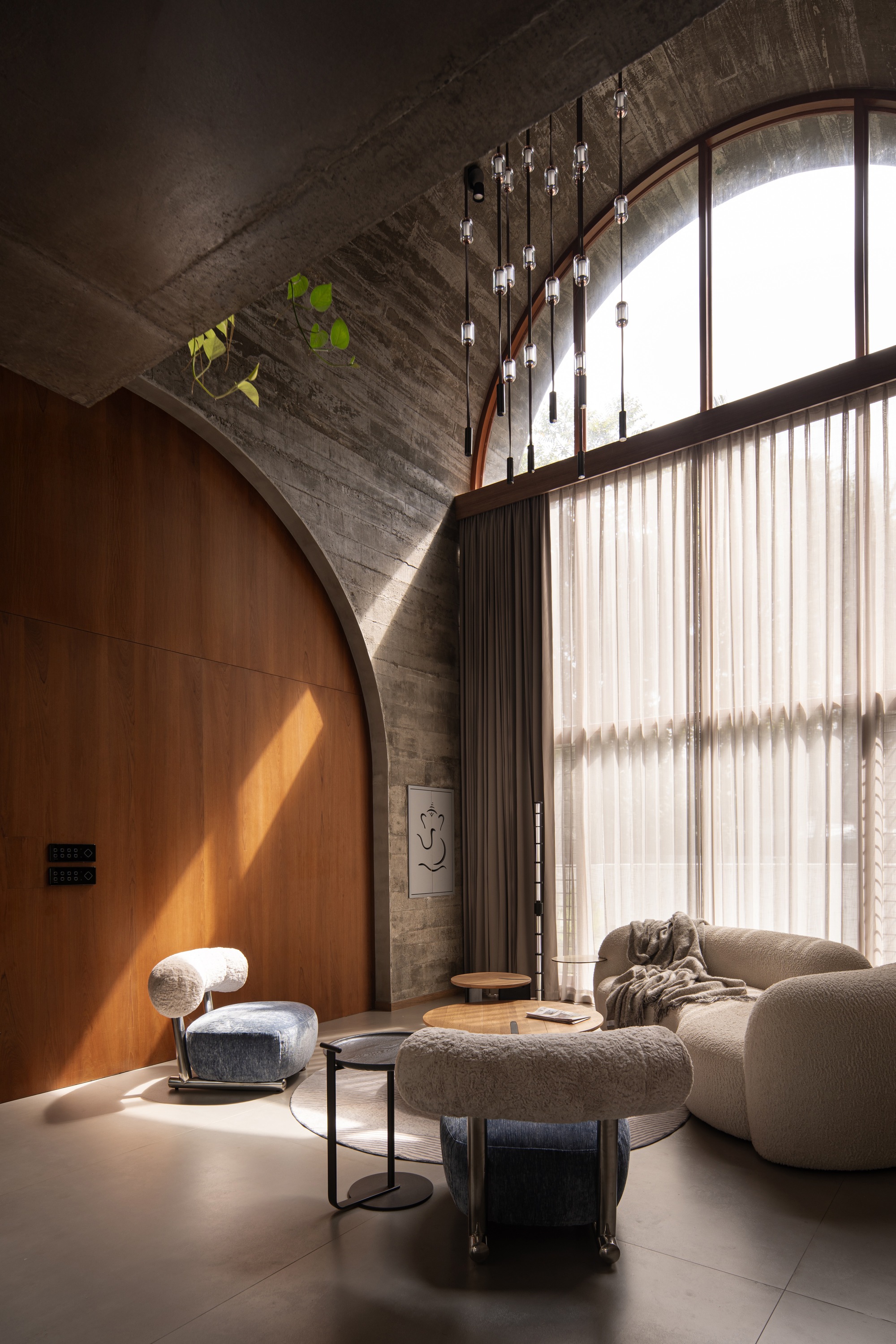 Curved timber wall beneath arched concrete vault with sheer curtains filtering daylight from tall windows