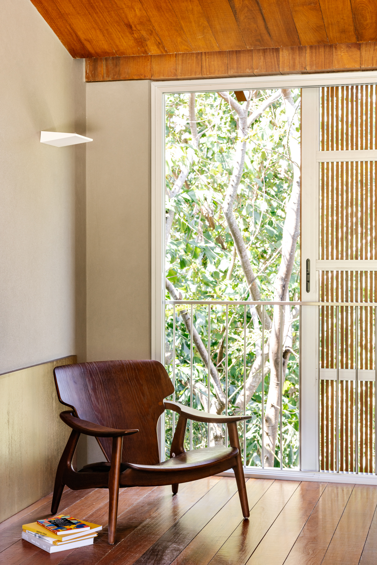 Interior corner with timber-panelled ceiling and glazed door opening to a garden with white-barked trees