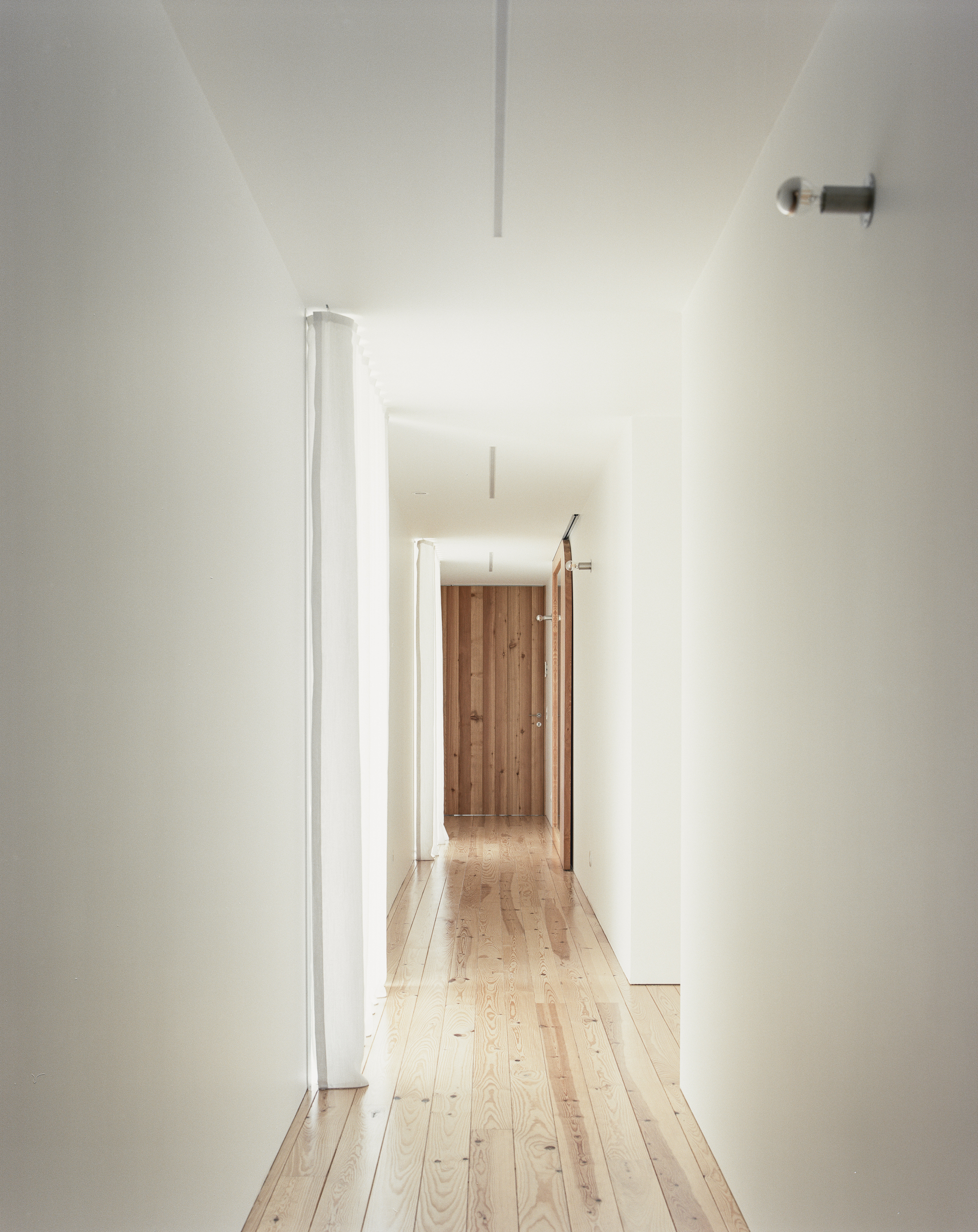 White-walled corridor with pale timber flooring and a recessed ceiling channel of light