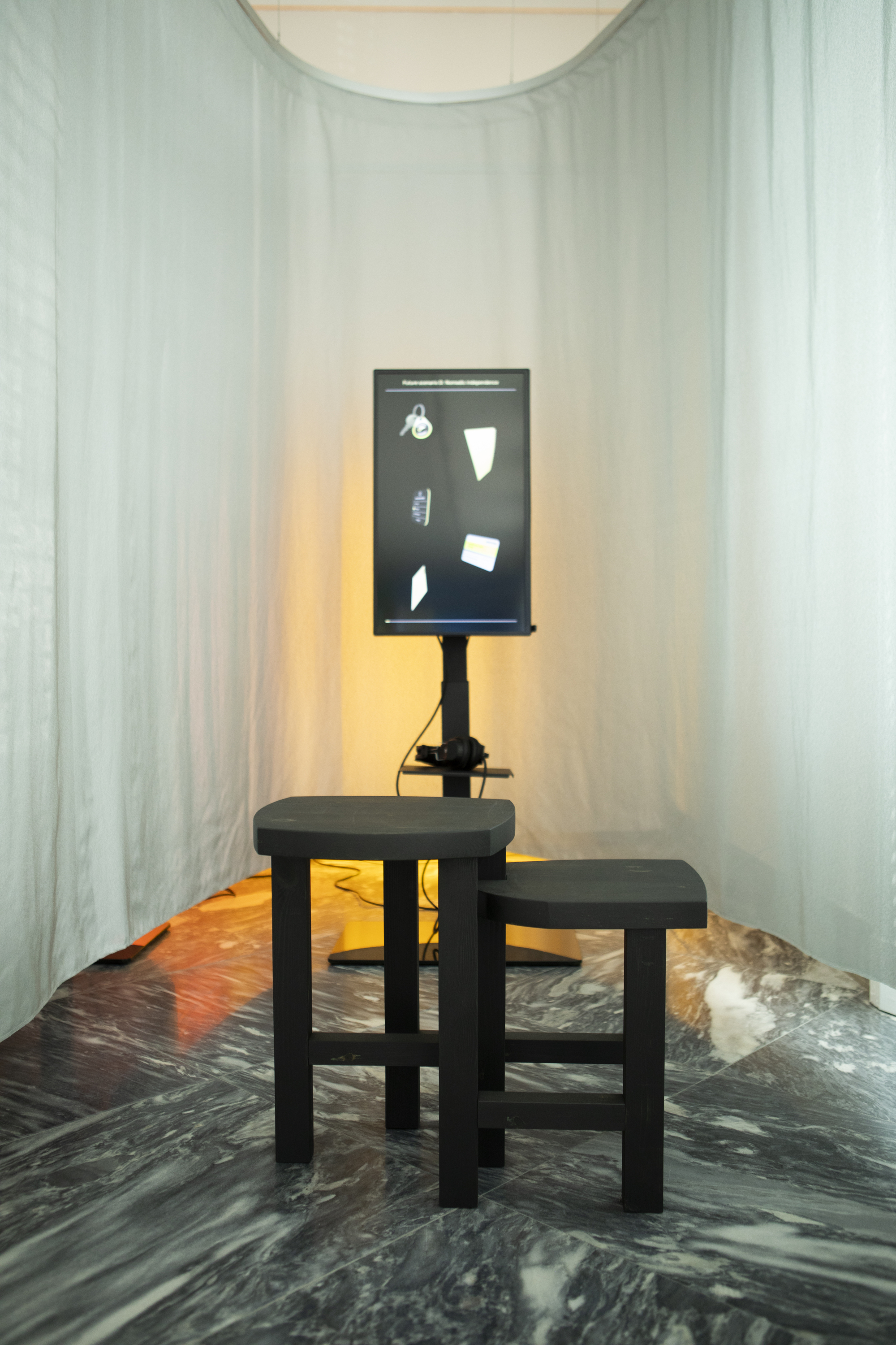 Black display panel and stools in curtained alcove with warm backlighting on marble floor