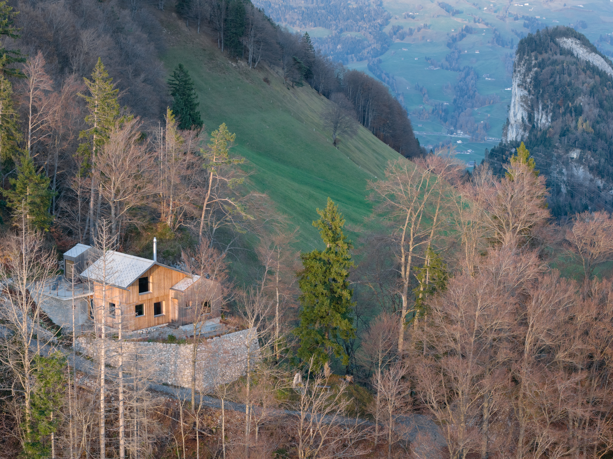 Aerial view of the timber volume on a gravel clearing among bare trees on a steep mountainside