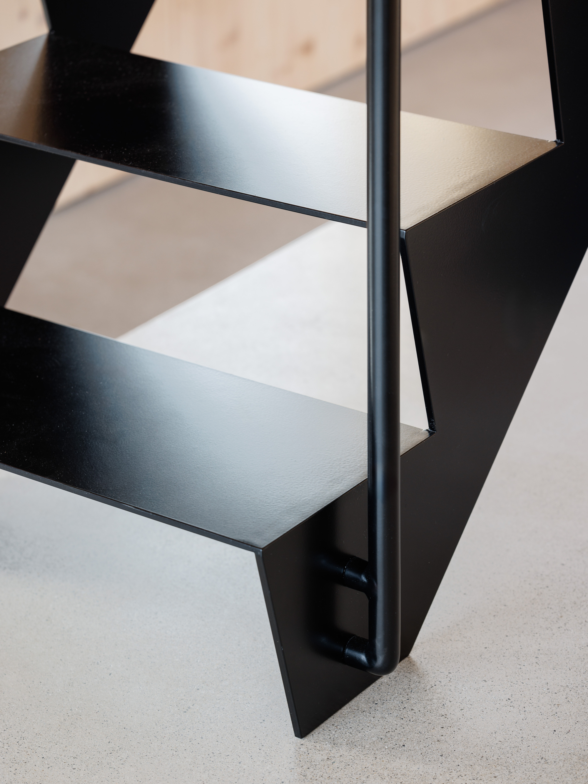Detail of black powder-coated steel stair treads and central spine against terrazzo flooring
