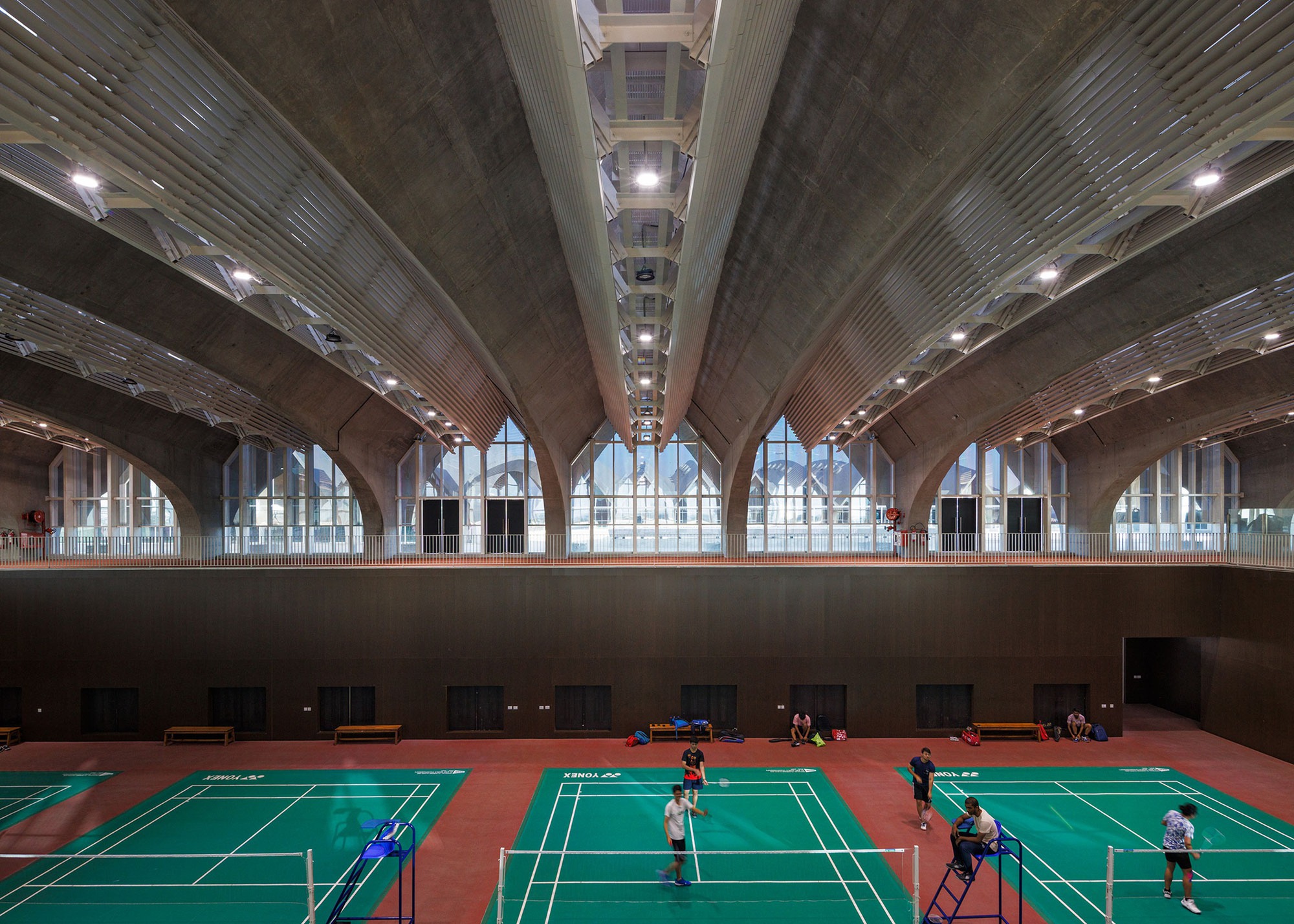 Interior sports hall with badminton courts under ribbed concrete vaults and clerestory windows