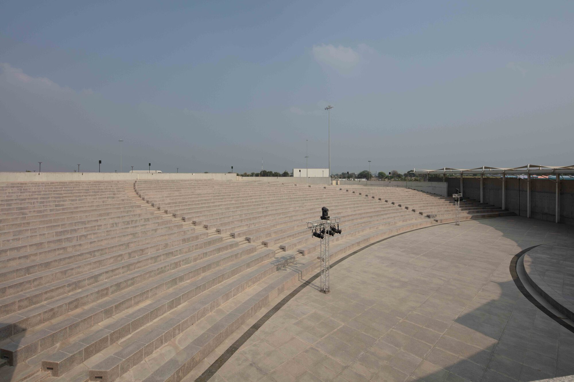 Wide view of curved amphitheatre seating with stone steps descending toward a central platform under clear sky