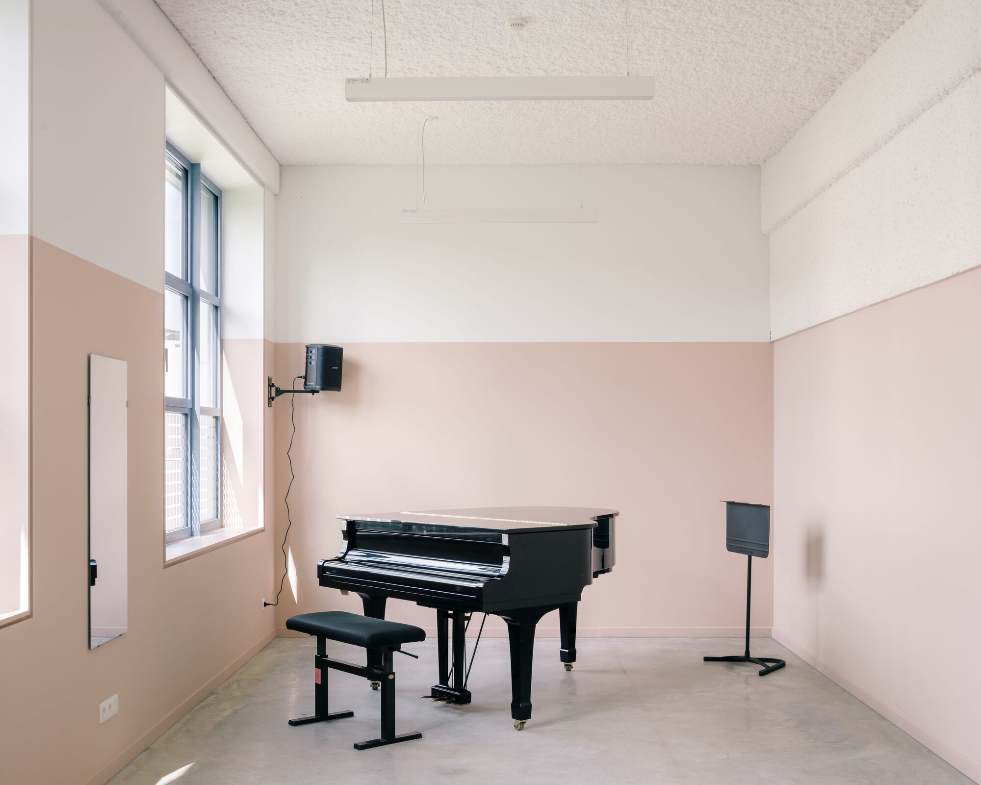 Music practice room with peach wainscoting and grand piano in daylight