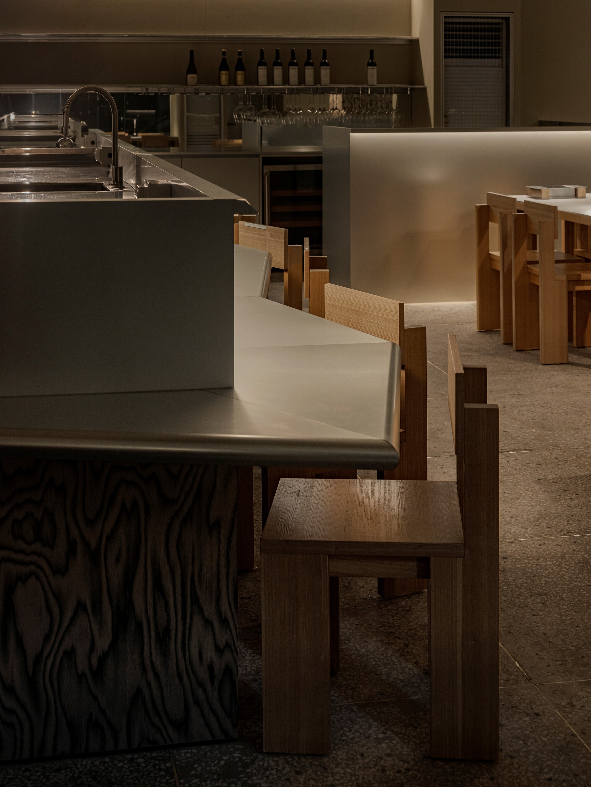 Interior dining area with timber chairs and metal counter beneath warm overhead lighting
