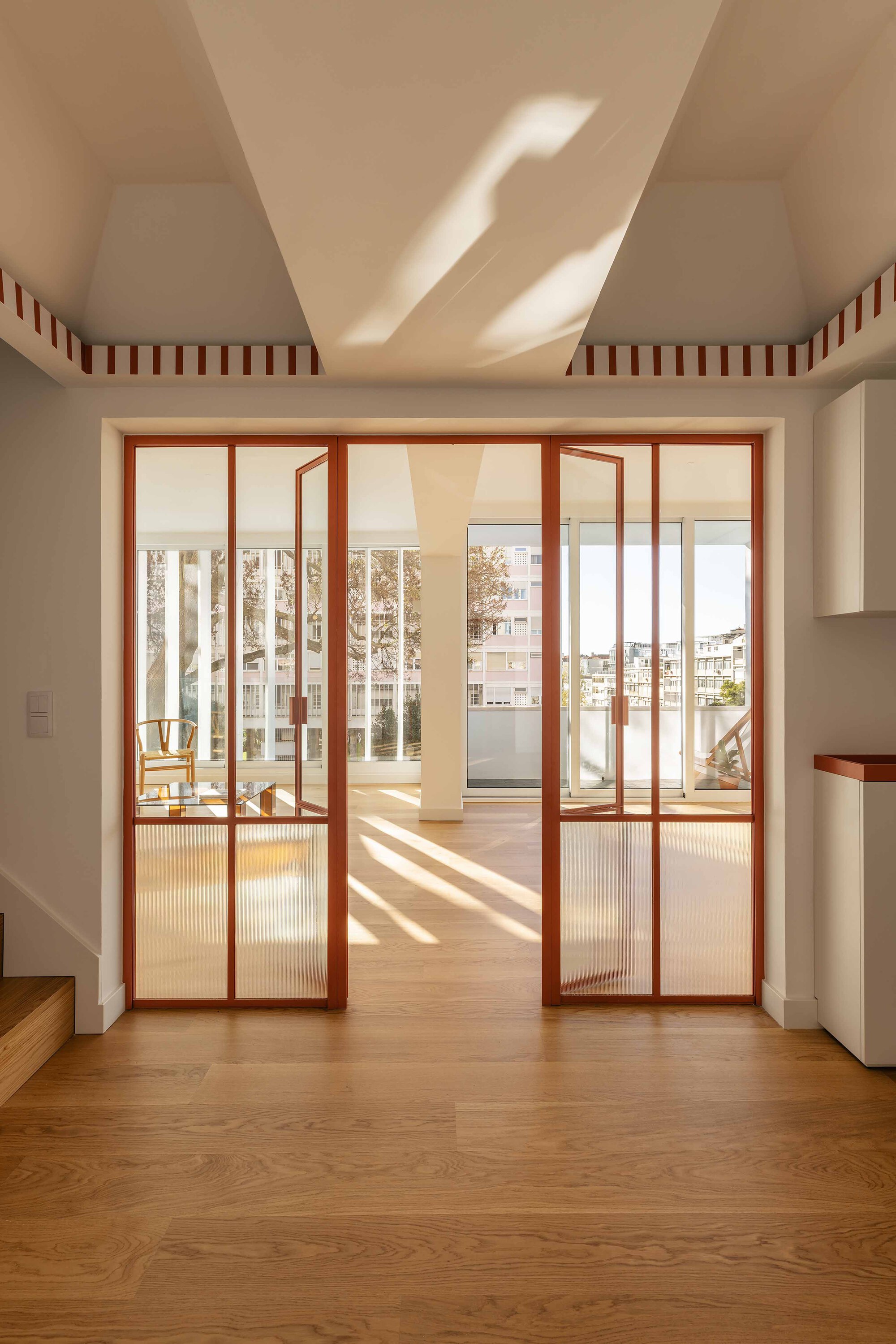 View through sliding glass doors with timber frames toward a balcony under afternoon light