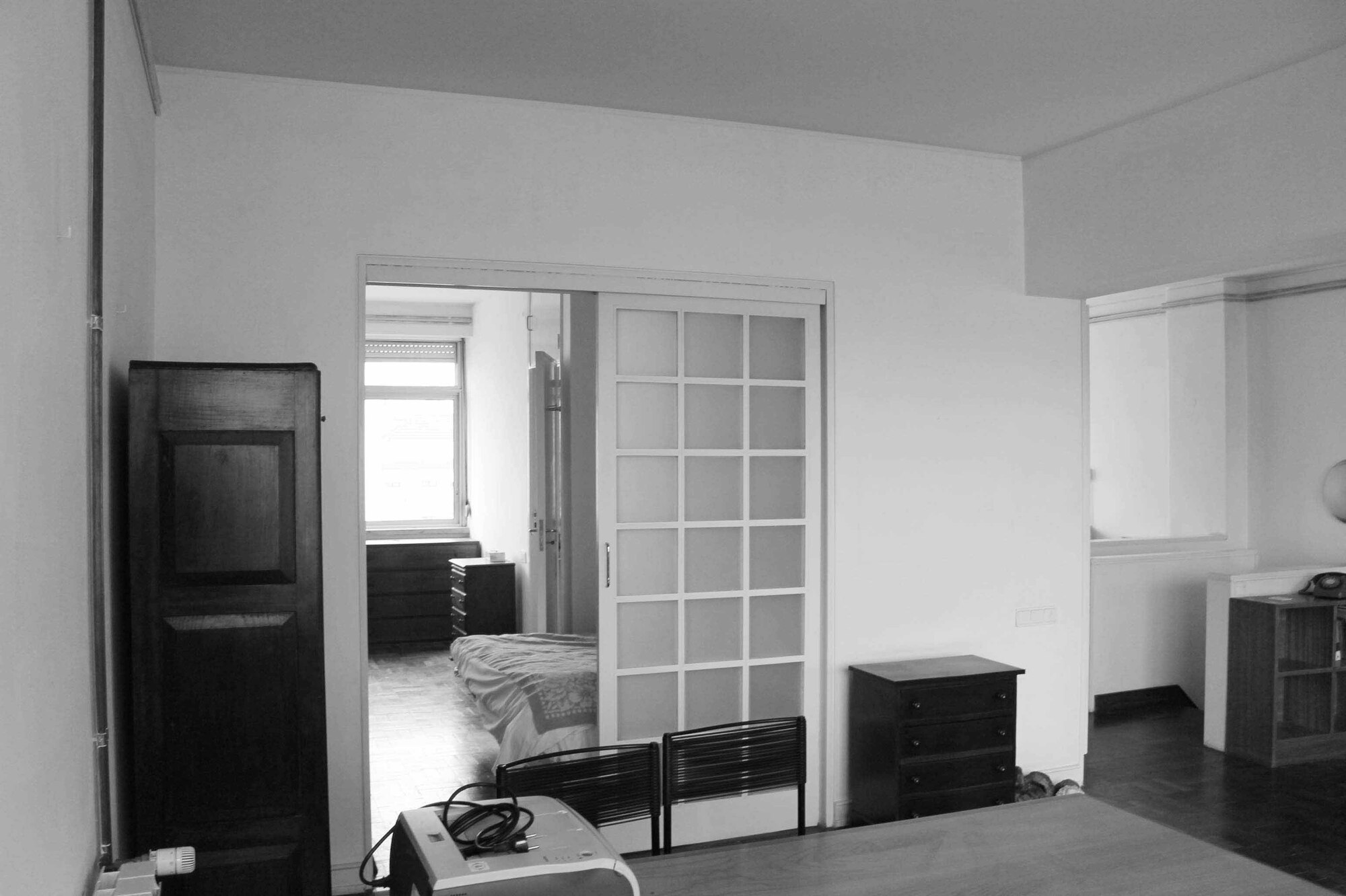 White gridded sliding door separating bedroom from adjacent living space with dark wood furniture