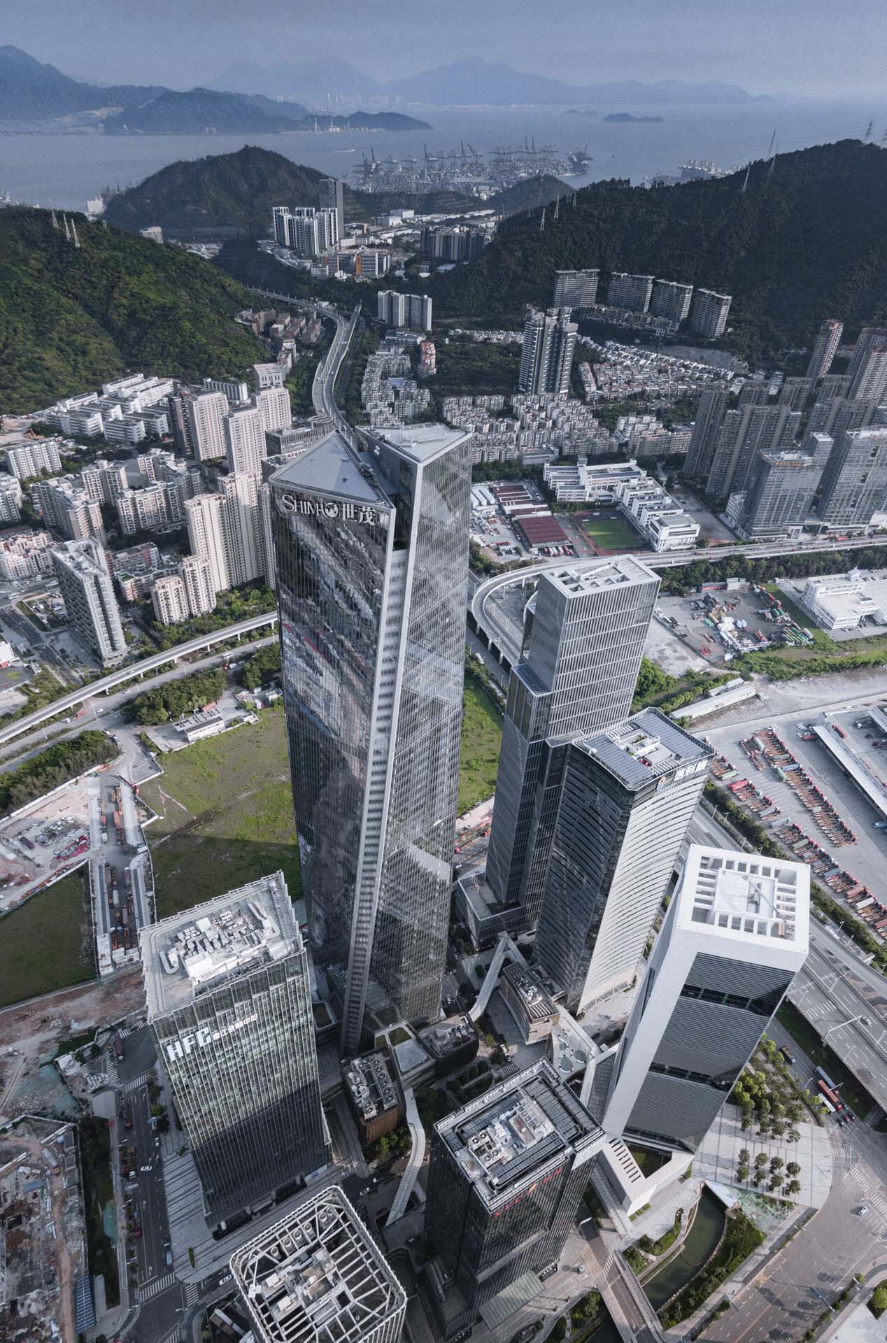Aerial view of the twisted tower complex surrounded by hillside housing and distant harbor