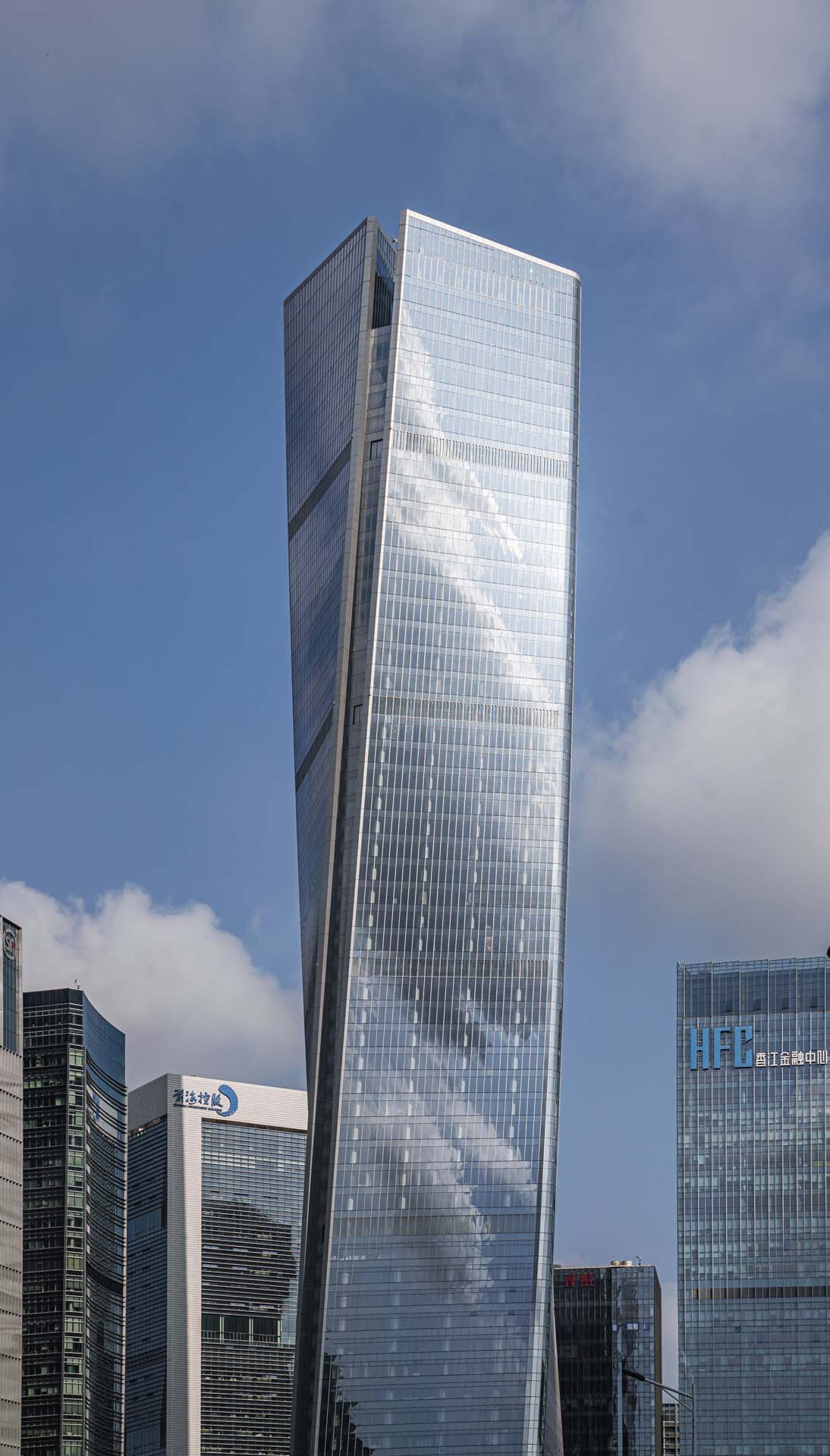 Angled facade of the glass tower showing diagonal structural bracing pattern against passing clouds