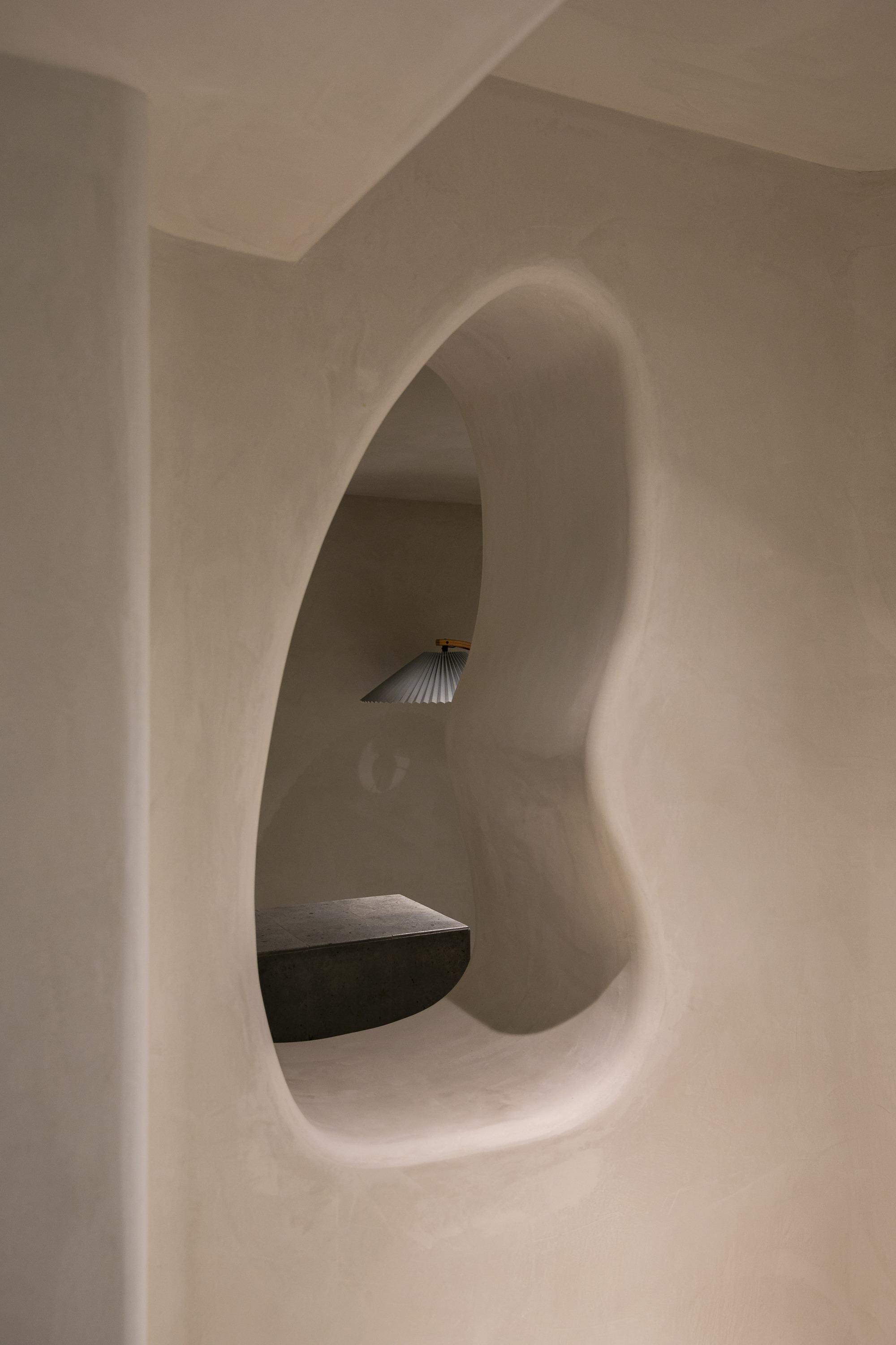 Arched alcove carved into plastered wall with integrated bench and shell-form sconce