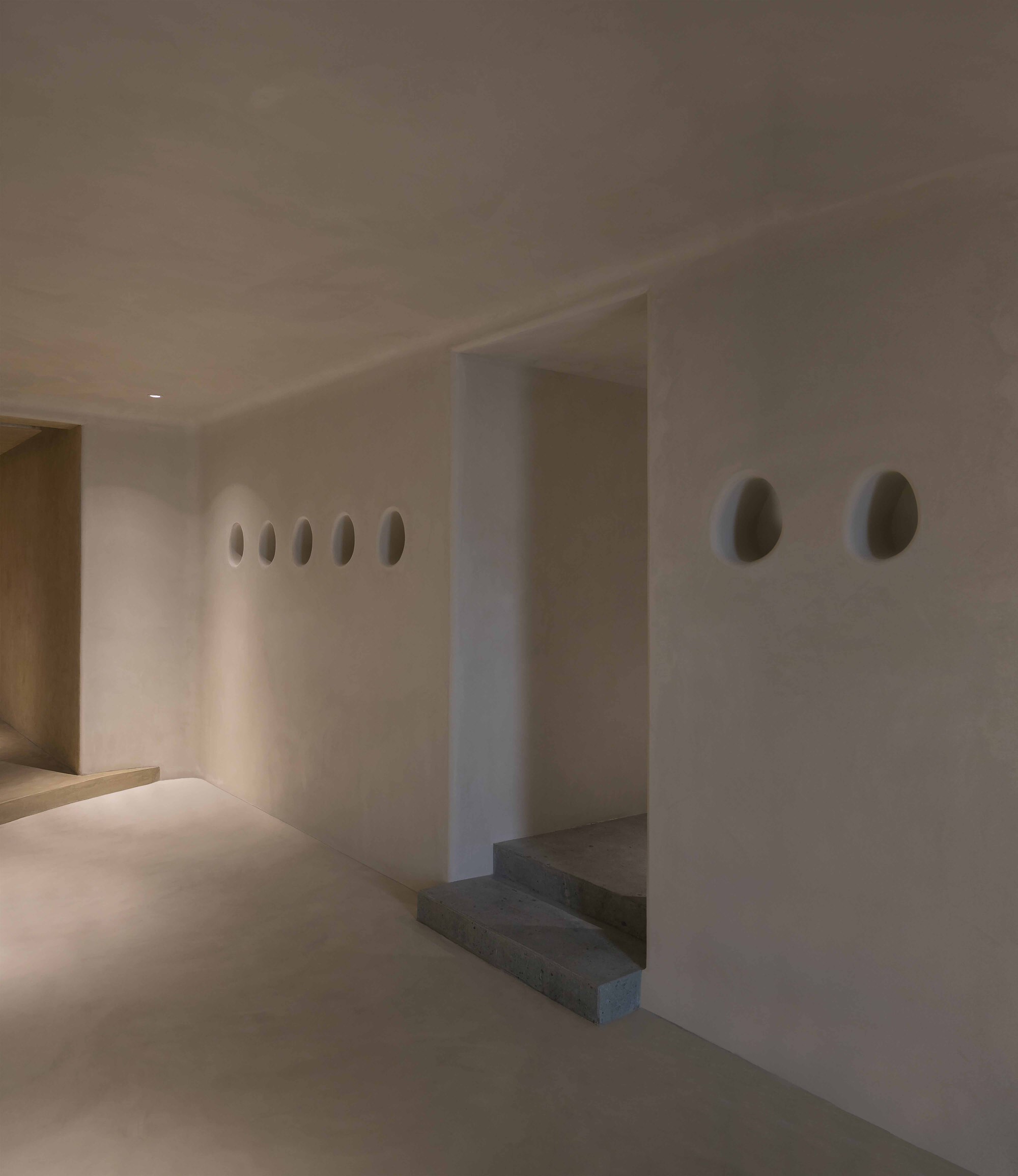 White plastered wall with oval niches and stone steps set into an alcove niche