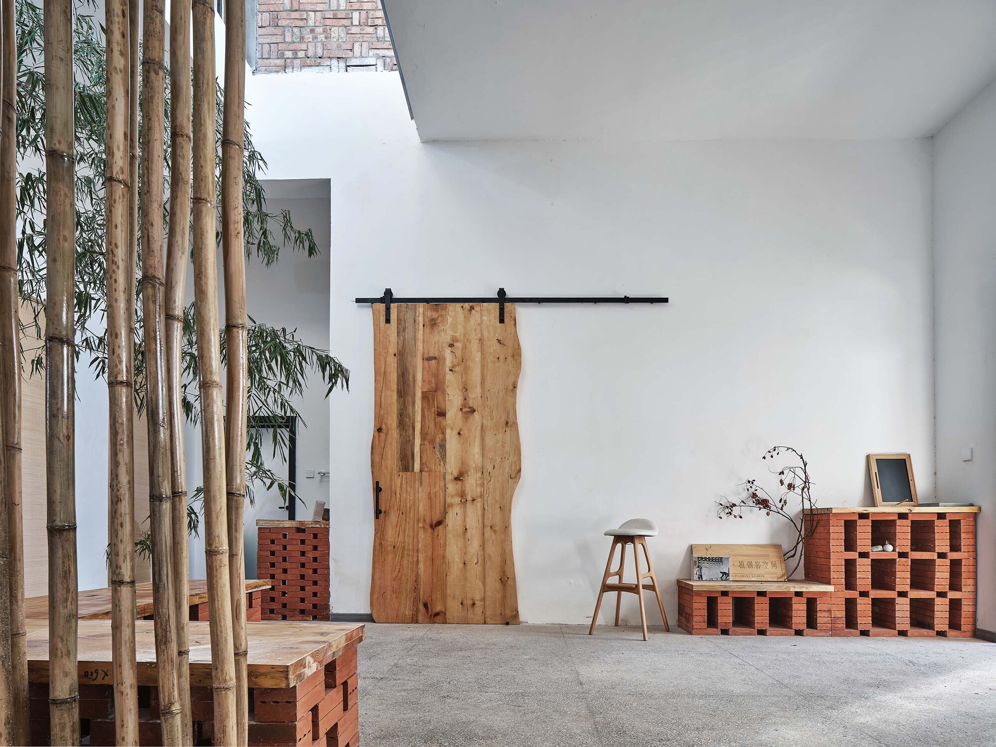 Sliding timber barn door on black rail with perforated brick seating and basketweave ceiling detail