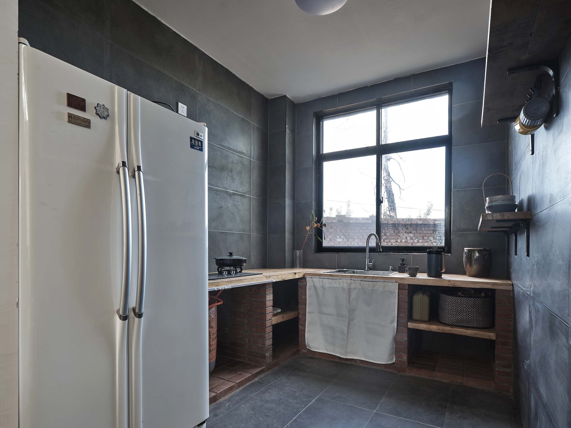 Kitchen corner with grey tile walls and timber counters under a grid window