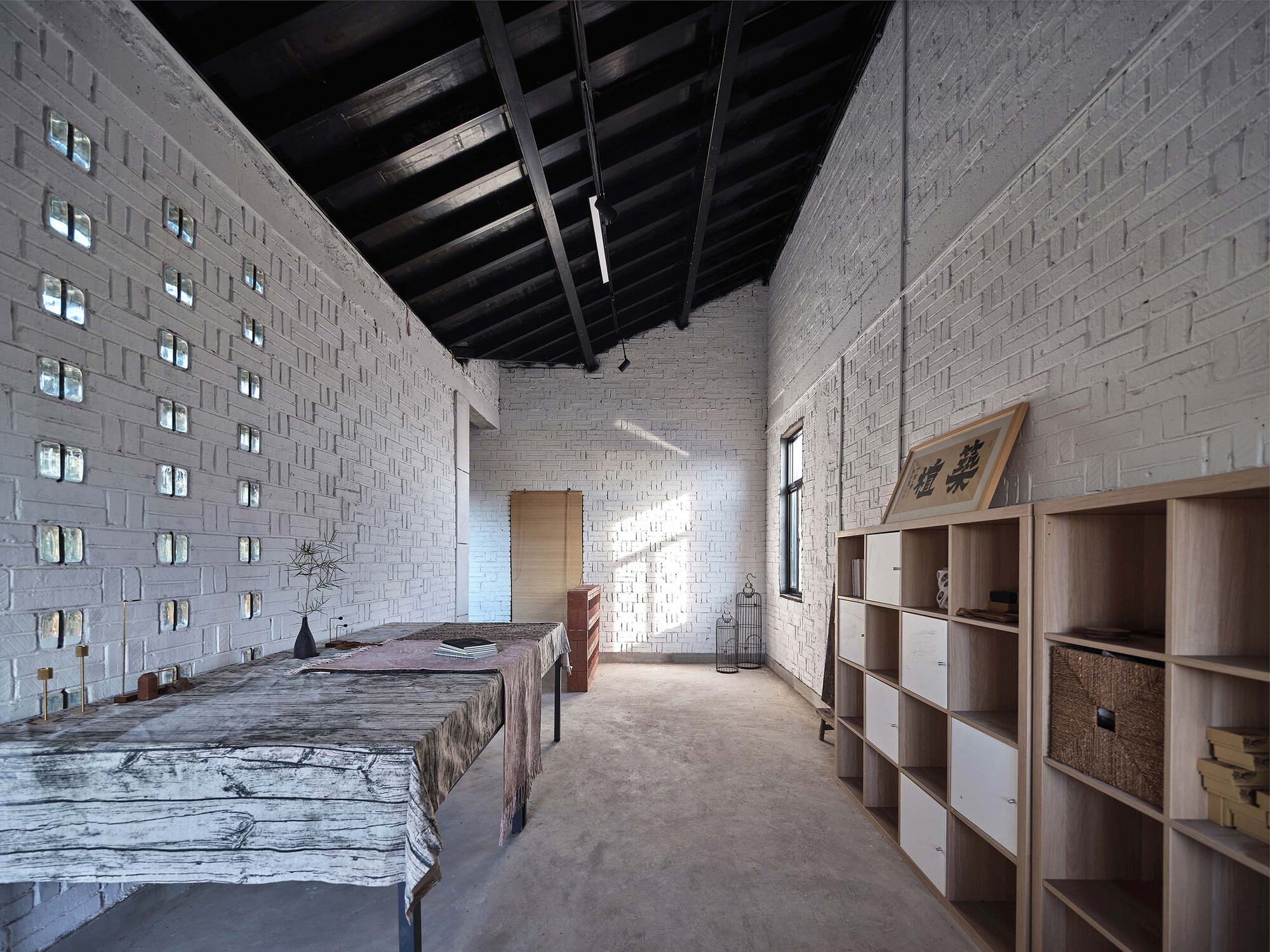 Bedroom with perforated white brick walls and exposed timber ceiling beams in afternoon light