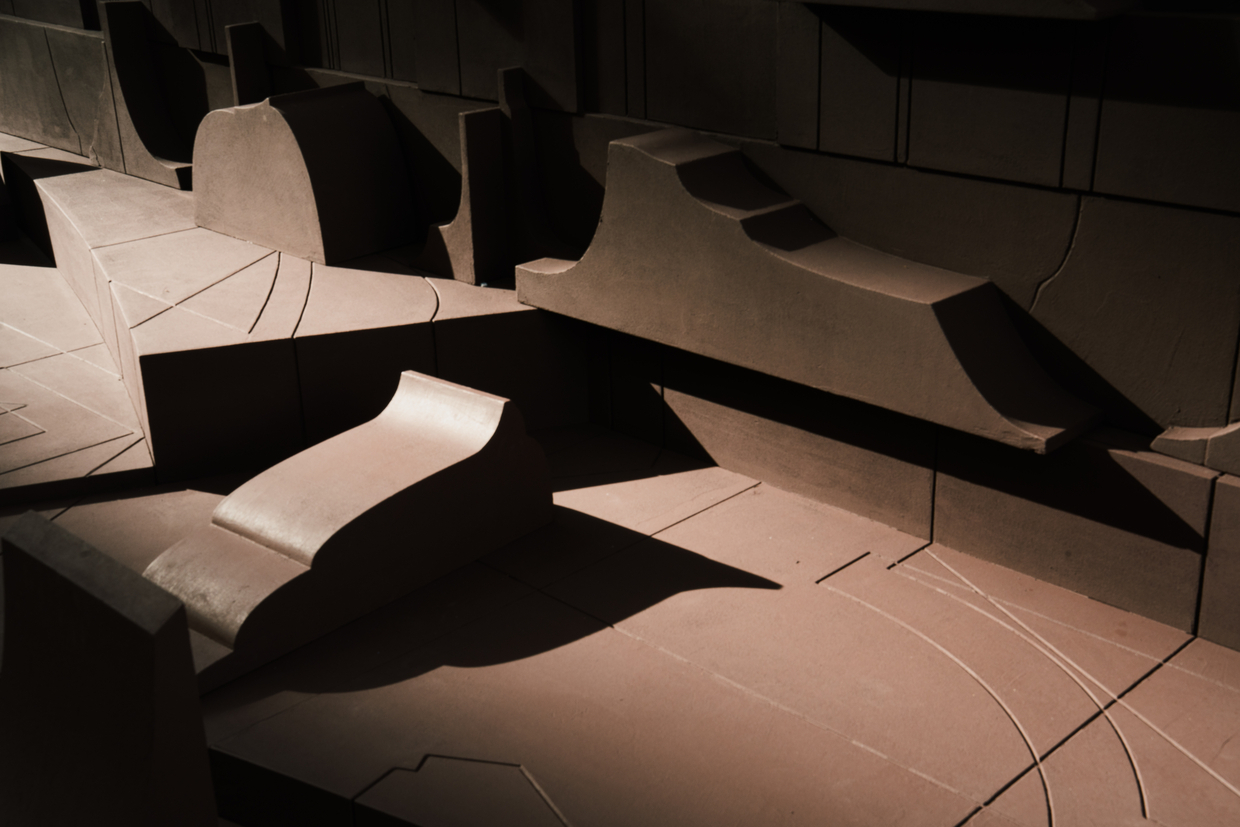Physical model showing interlocking angular volumes and courtyards under dramatic artificial lighting