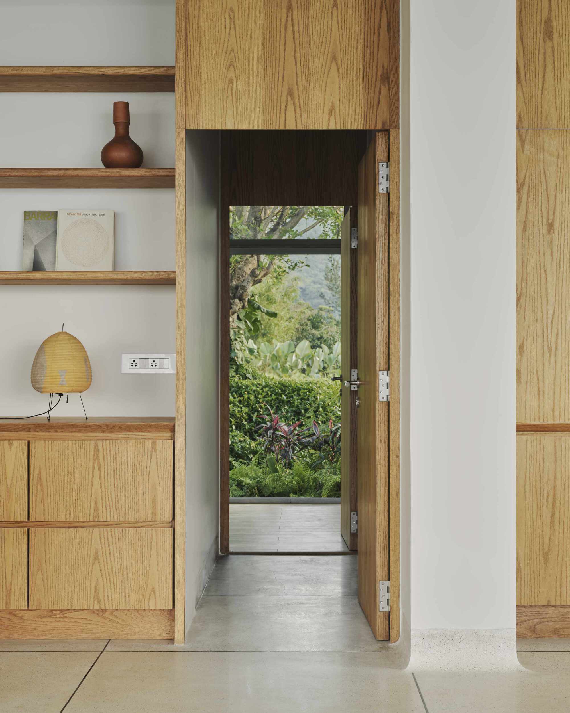 Narrow passageway framed by oak cabinetry leading to glazed door and garden beyond