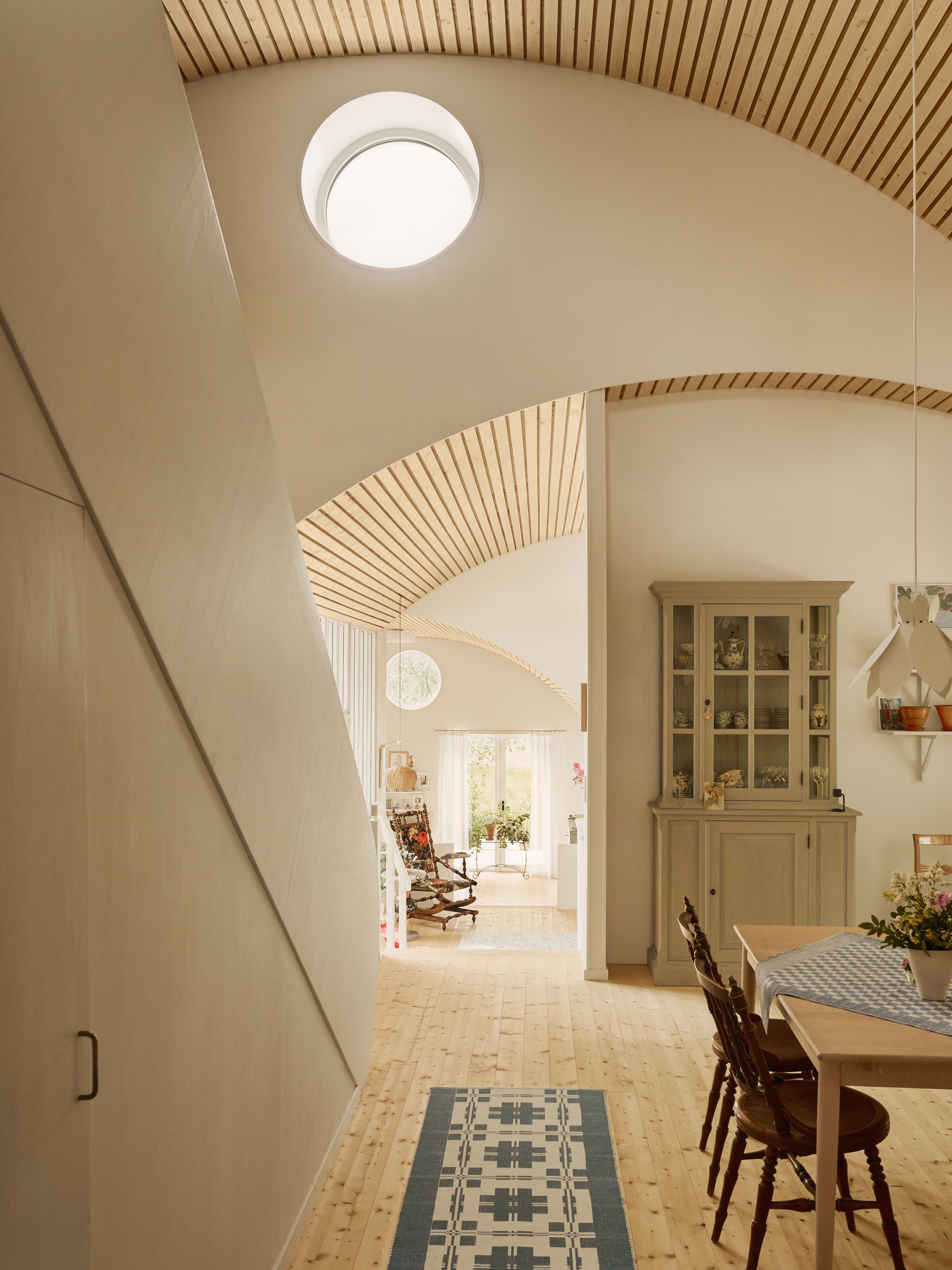 Arched doorway with ribbed wooden ceiling detail leading through dining space to rocking chair