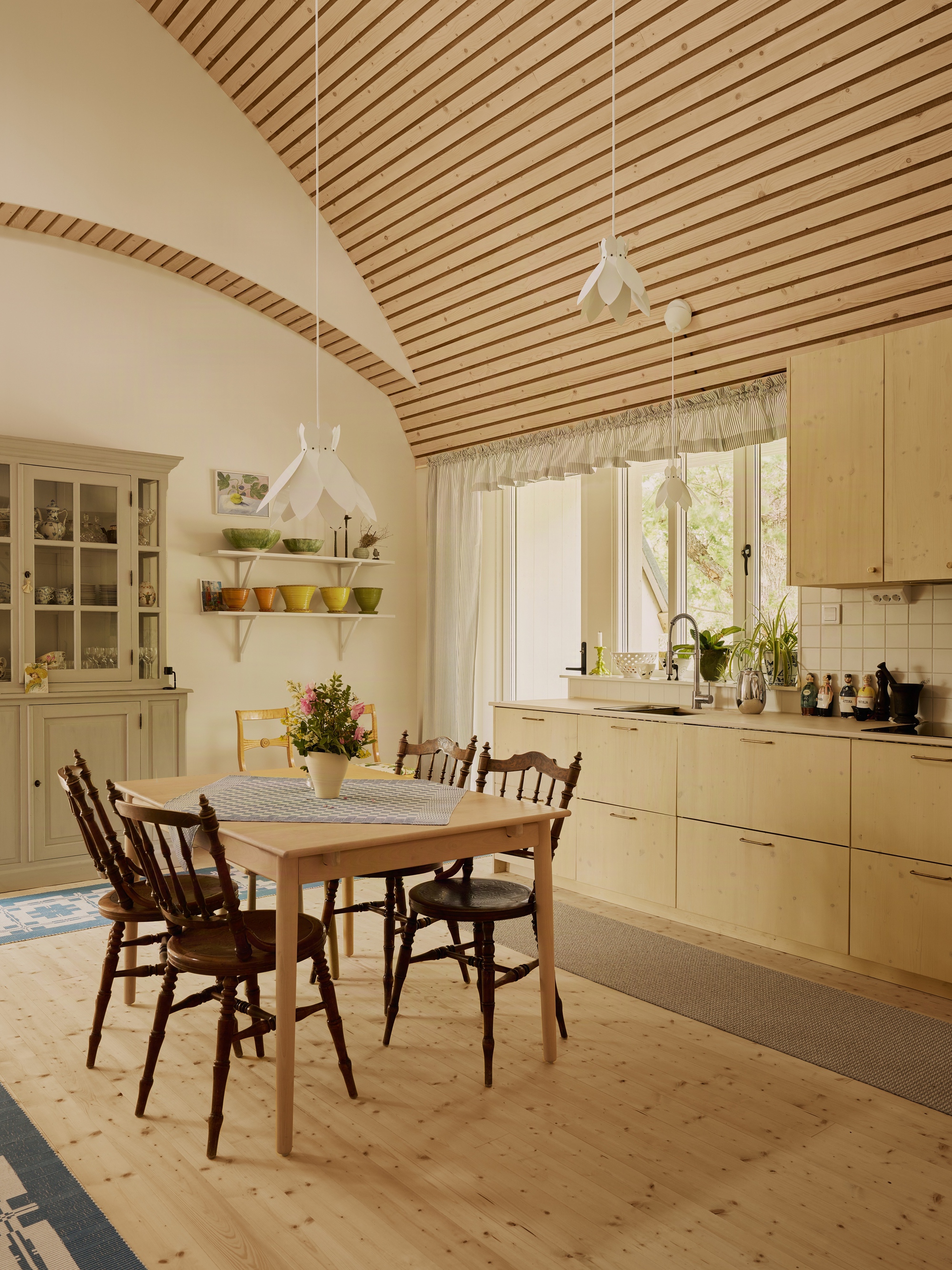 Kitchen and dining area with vaulted wood ceiling and patterned runner on pine flooring