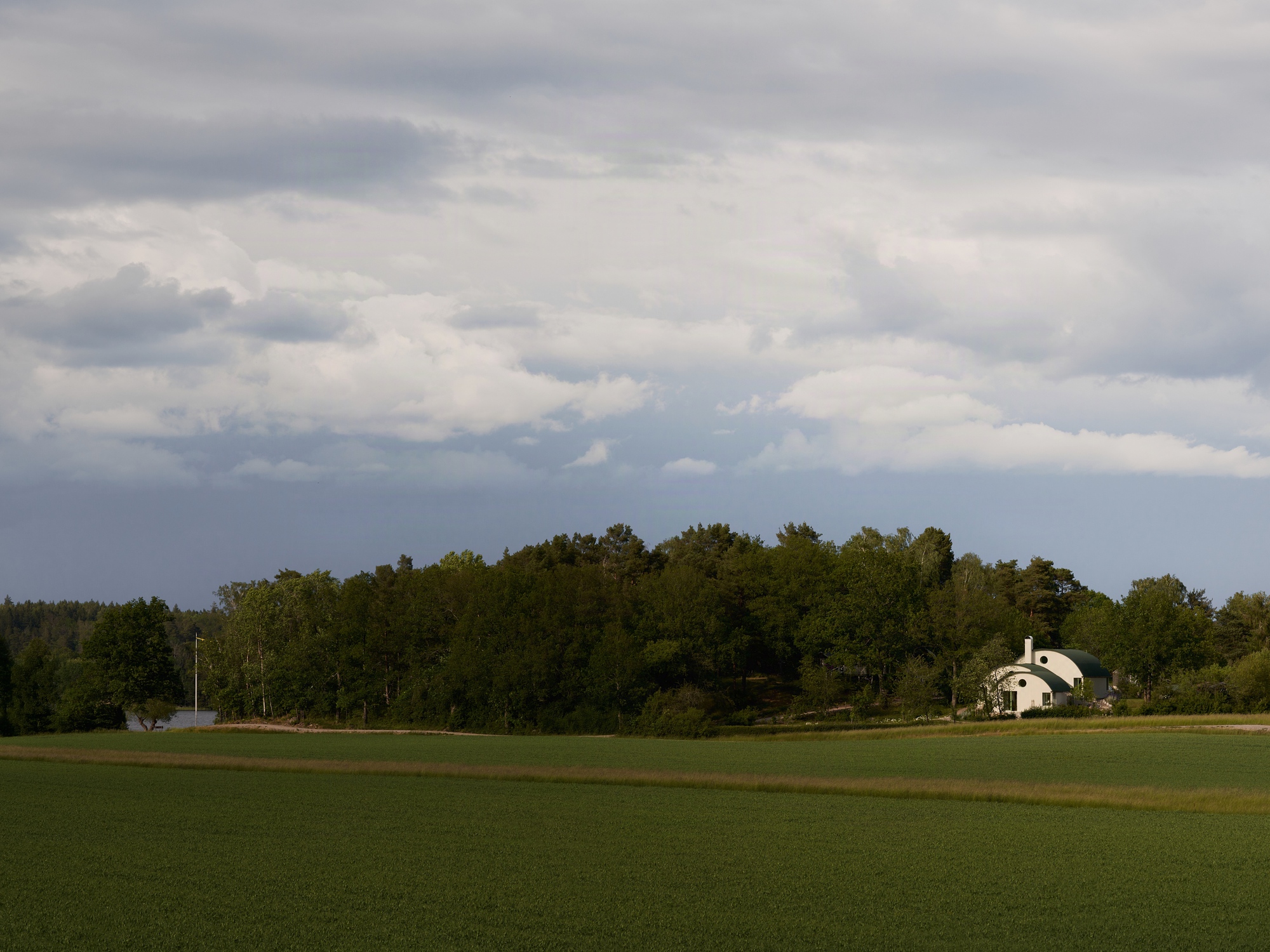 Distant view of the white dome structure nestled among trees at the edge of a green field