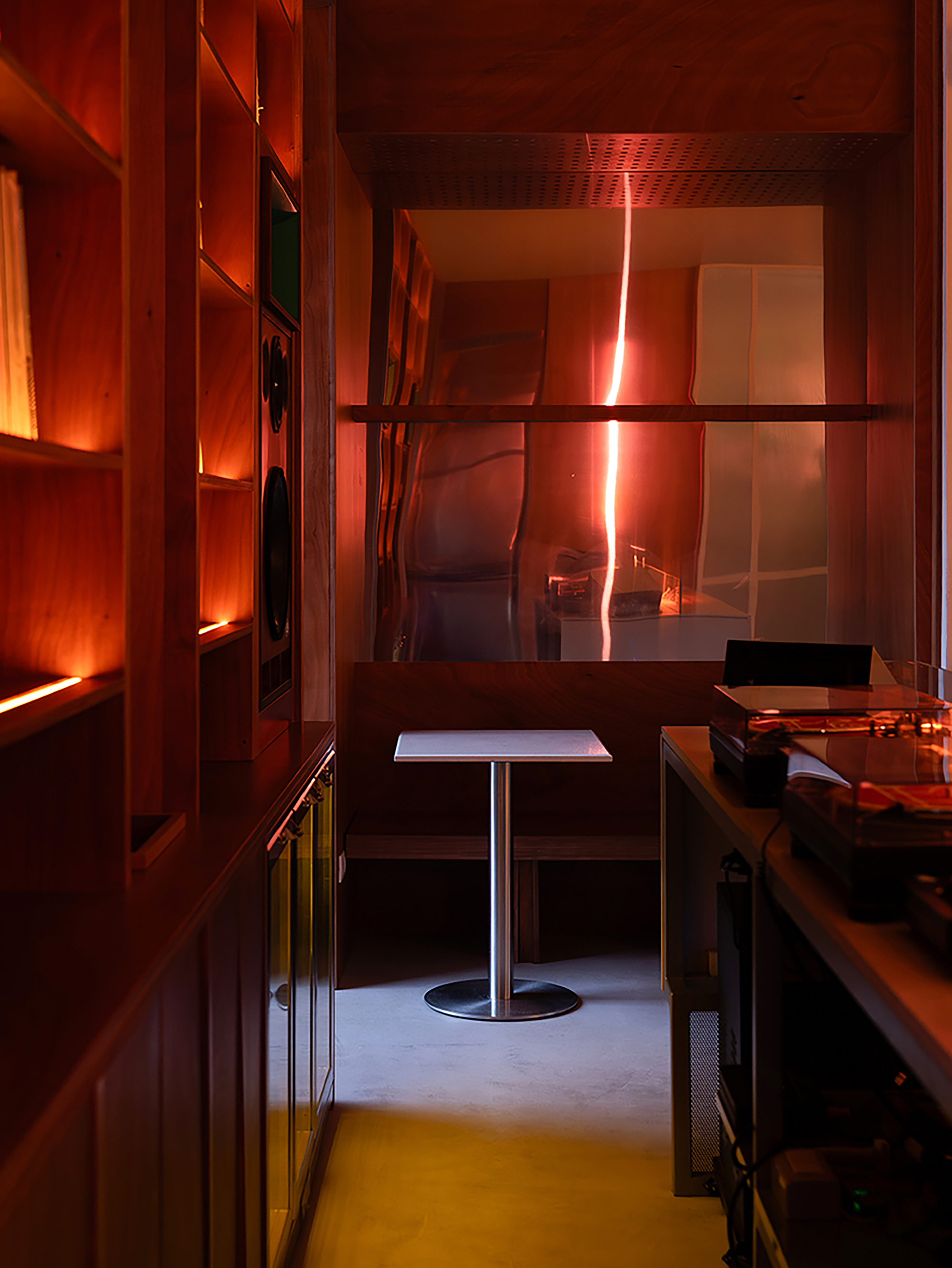 Interior booth with square table reflecting orange sunset light through glass partitions