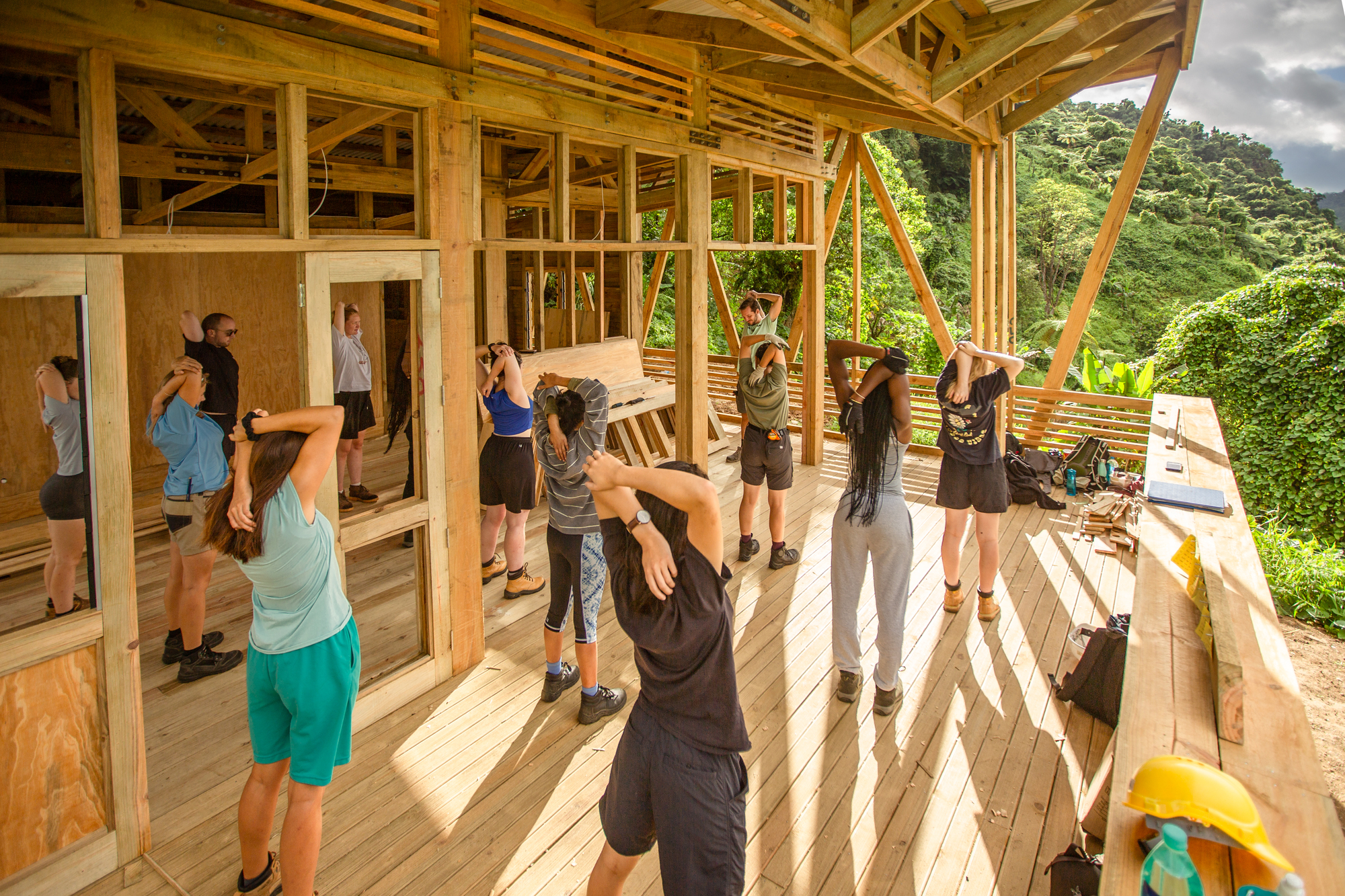 Construction workshop in progress with participants assembling timber frame elements on the plywood floor