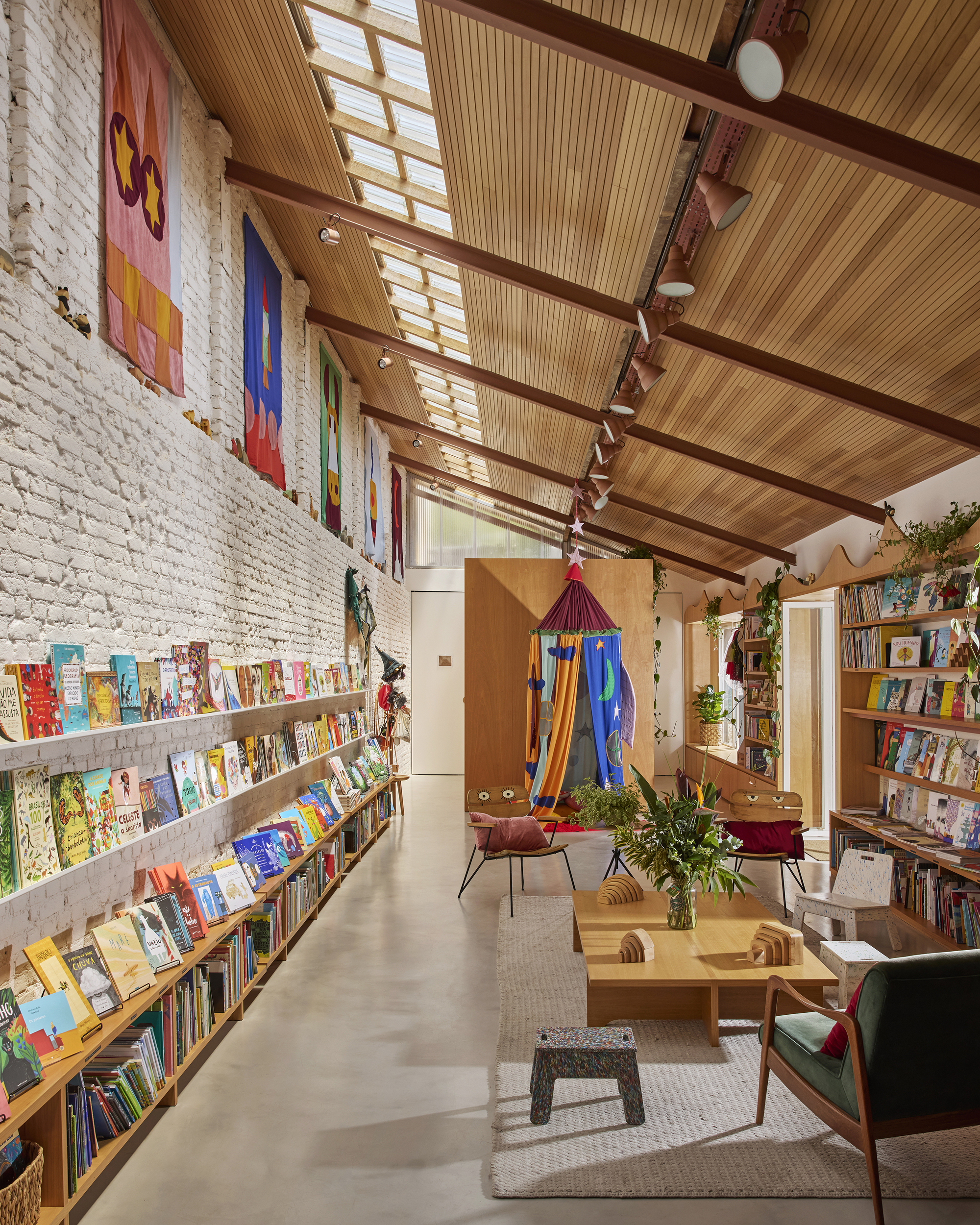 Long view through the bookshop showing timber ceiling, painted brick wall and central reading area