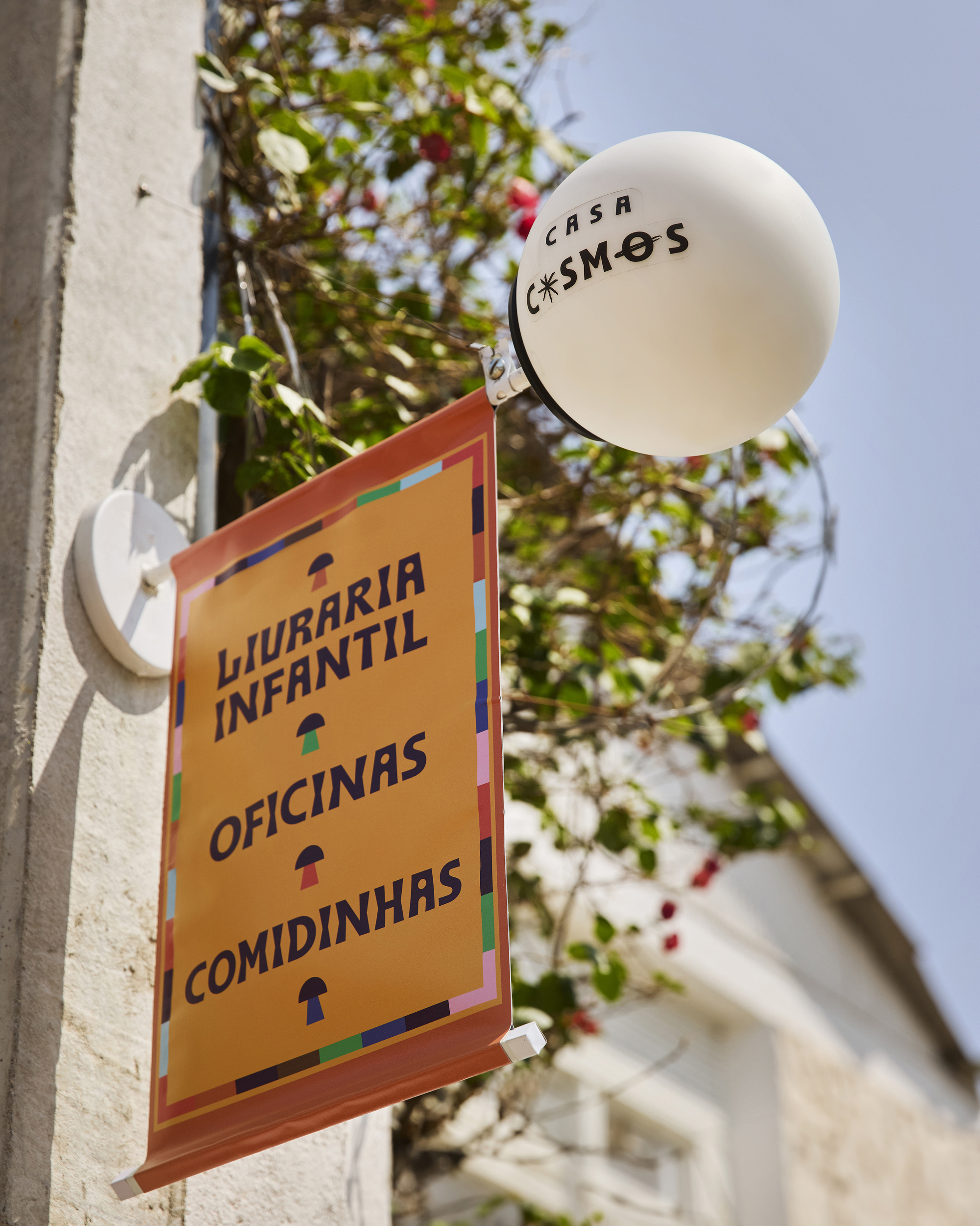 Signage detail showing circular orb light and hanging directory board against leafy trees