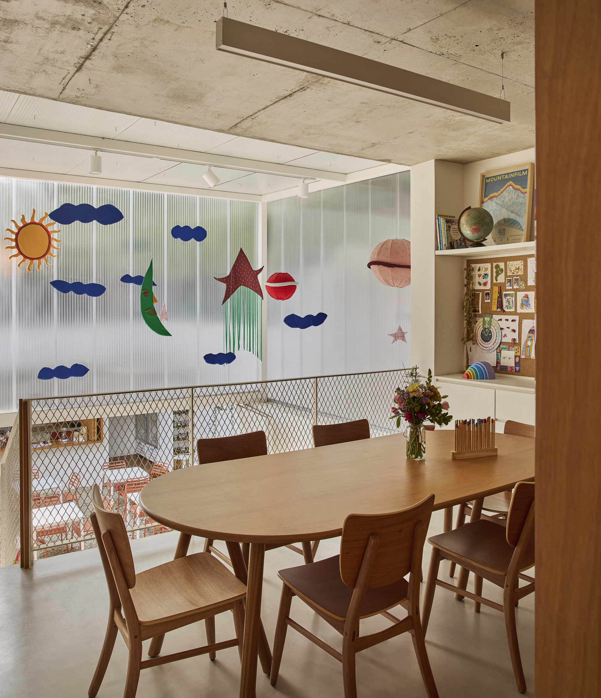 Dining area with exposed concrete ceiling and translucent partition decorated with sun and cloud motifs