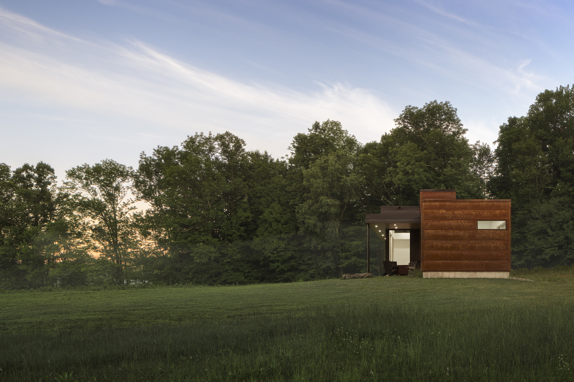 End elevation showing horizontal wood cladding and central glazed opening at sunset