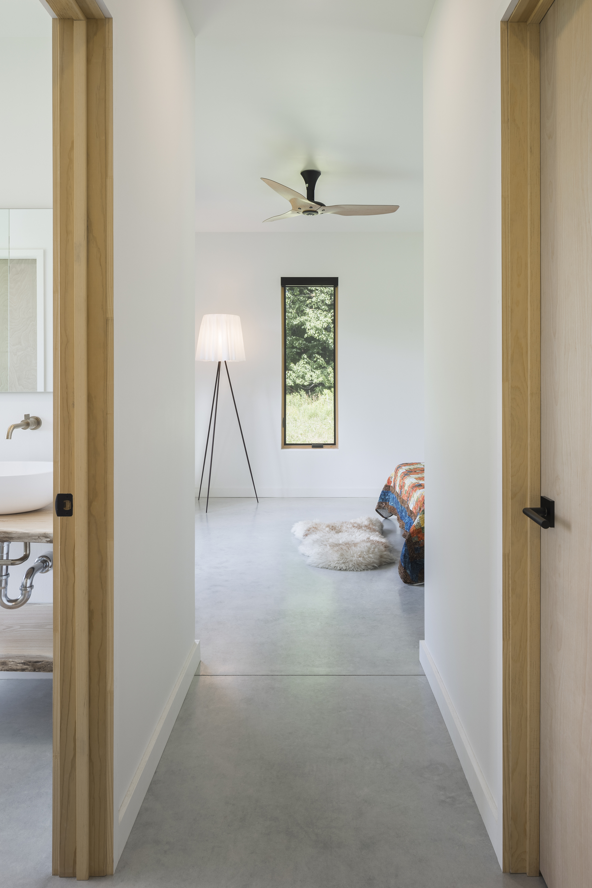 Hallway view with light wood door frames, polished concrete floor, and vertical window