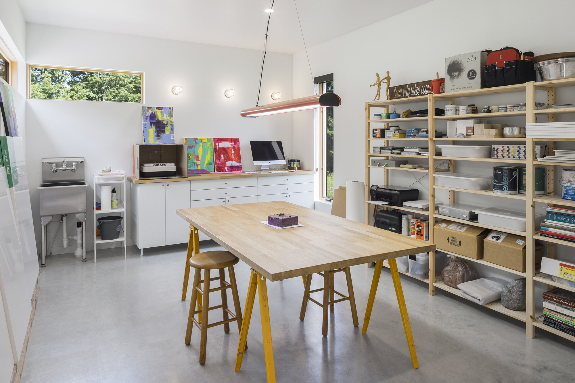 Workshop space with open shelving, work table on yellow trestle legs, and polished concrete floor