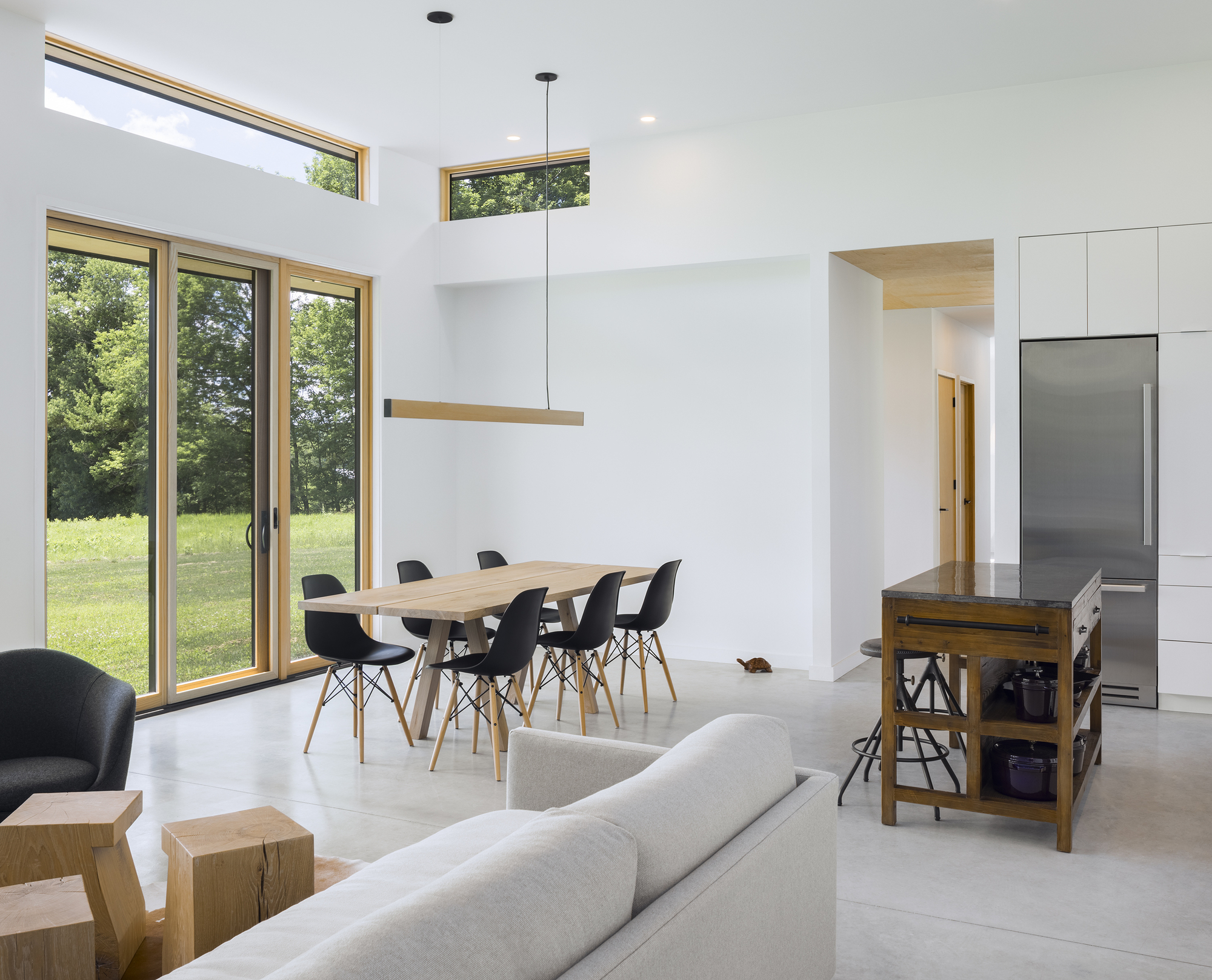 Open-plan living and dining space with clerestory windows overlooking a green meadow