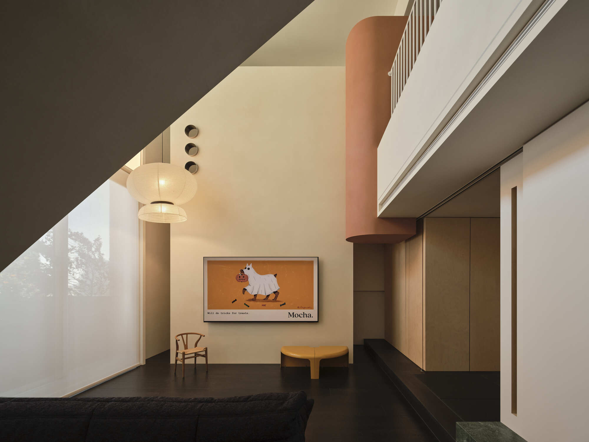 Angled ceiling plane meeting white walls beneath mezzanine level with pendant sphere light illuminating at dusk