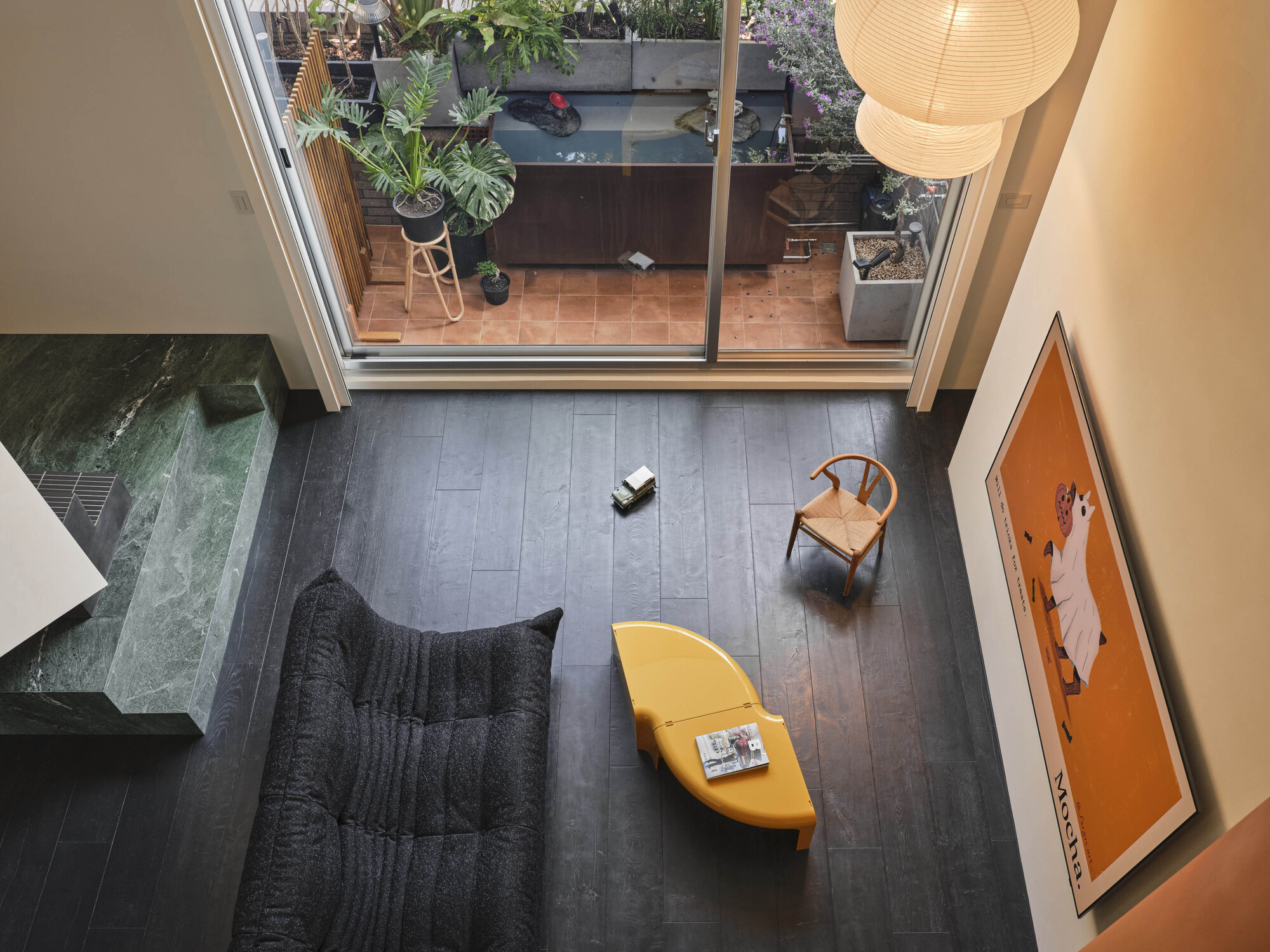 Overhead view of living room with glazed doors opening to planted terrace above