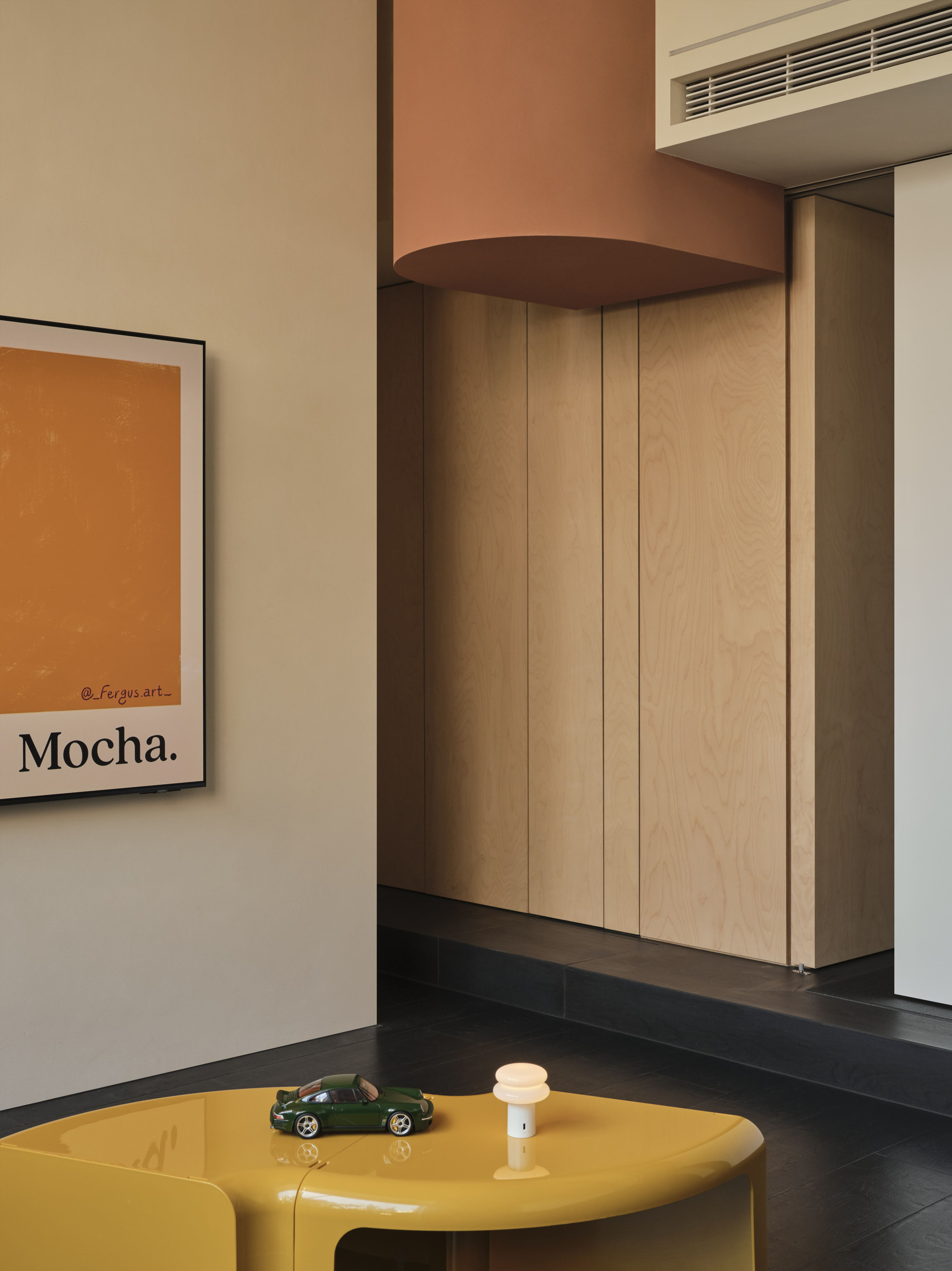 Light wood storage wall with rounded soffit beneath a recessed linear air vent