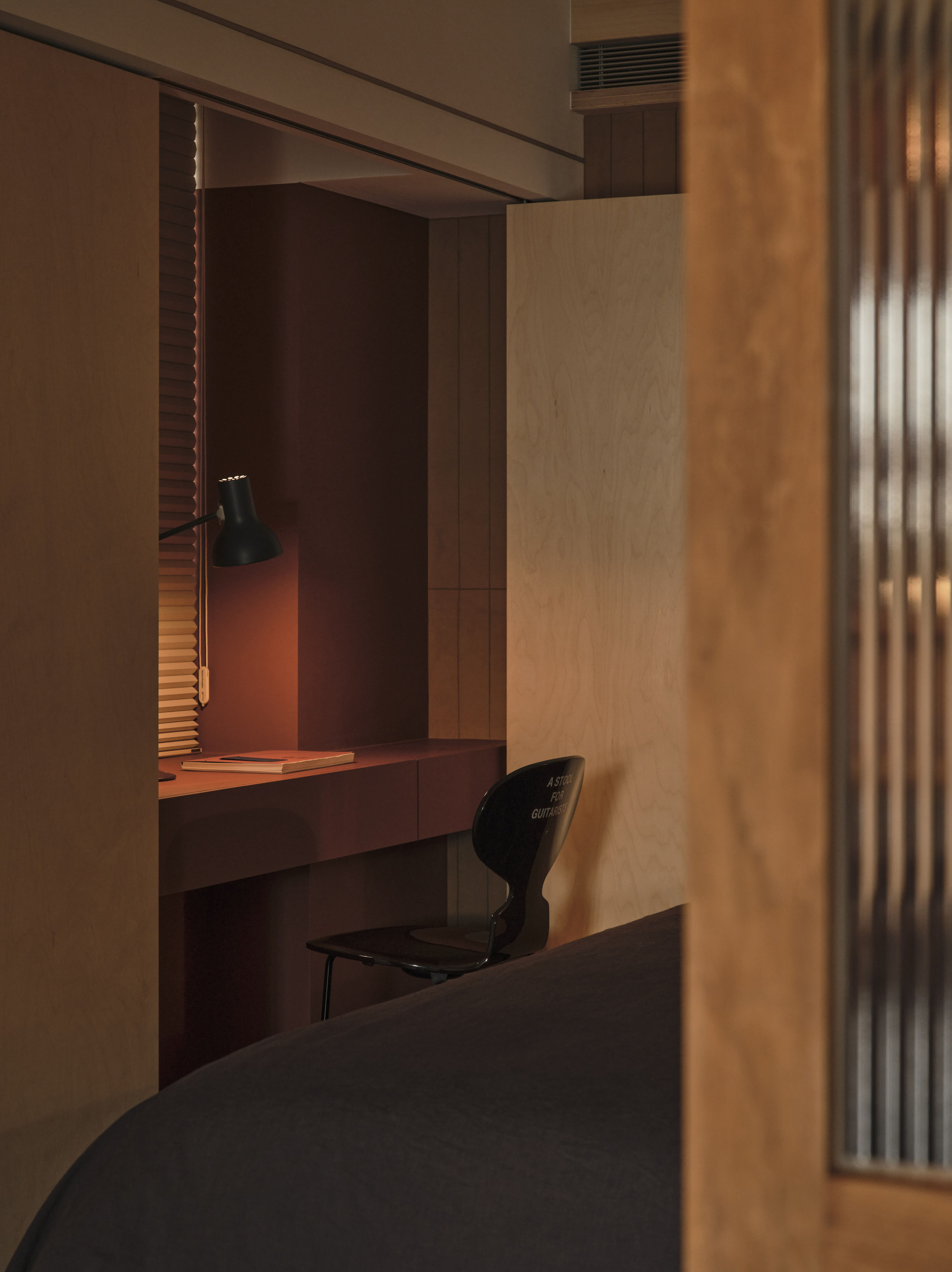 Built-in desk alcove with timber paneling and a black pendant lamp casting warm light